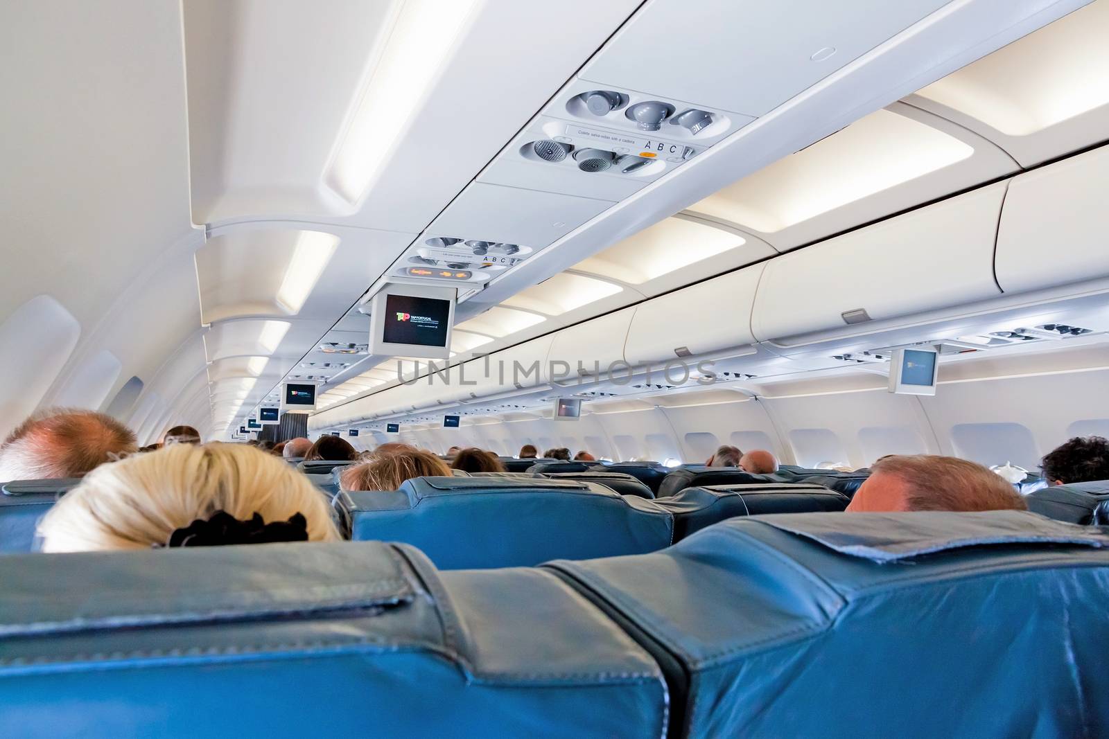 Lisbon, Portugal - June 9, 2013: Inside of an Airbus A320 - passenger seats during flight - airline TAP Portugal. Rows with passengers heads from behind.