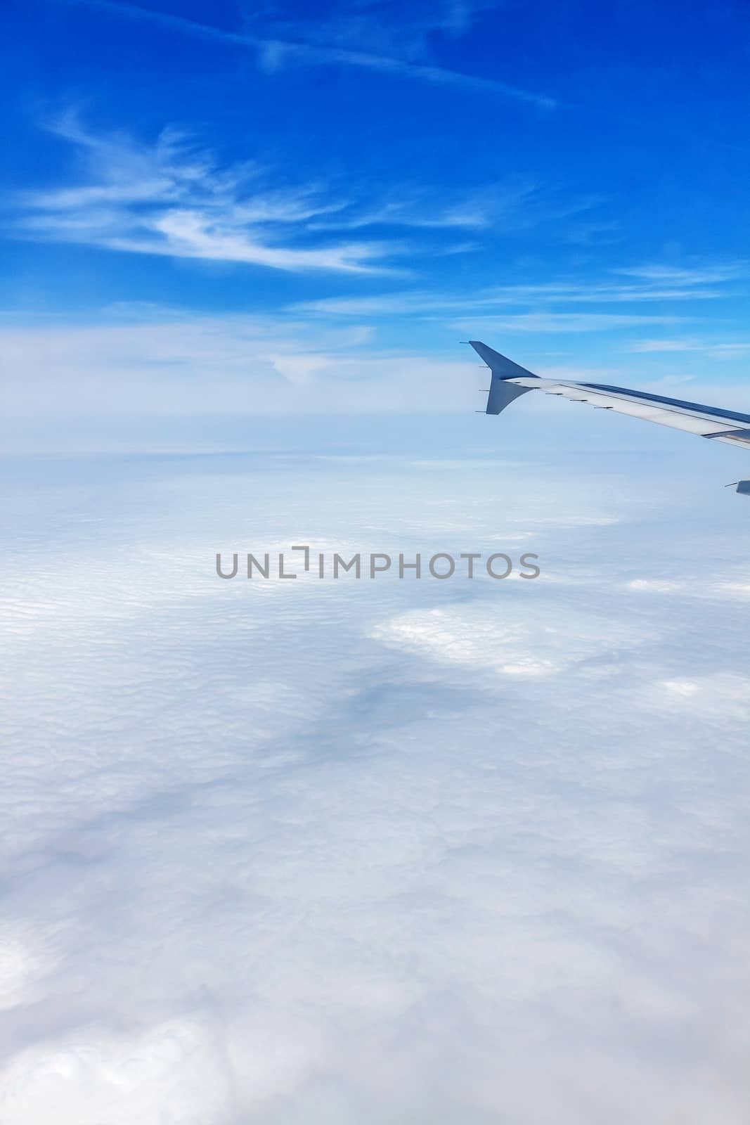 Flight with Airplane - window view with wing over the clouds.