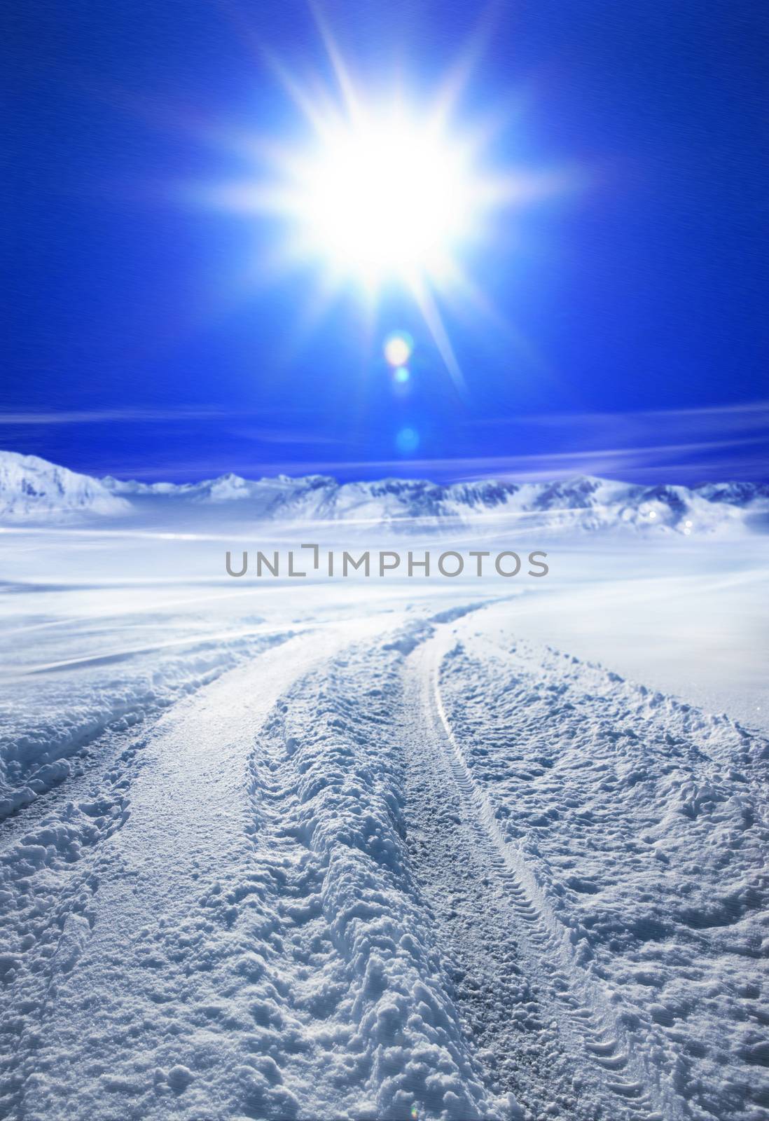 Snow covered road in winter with mountains in the distance