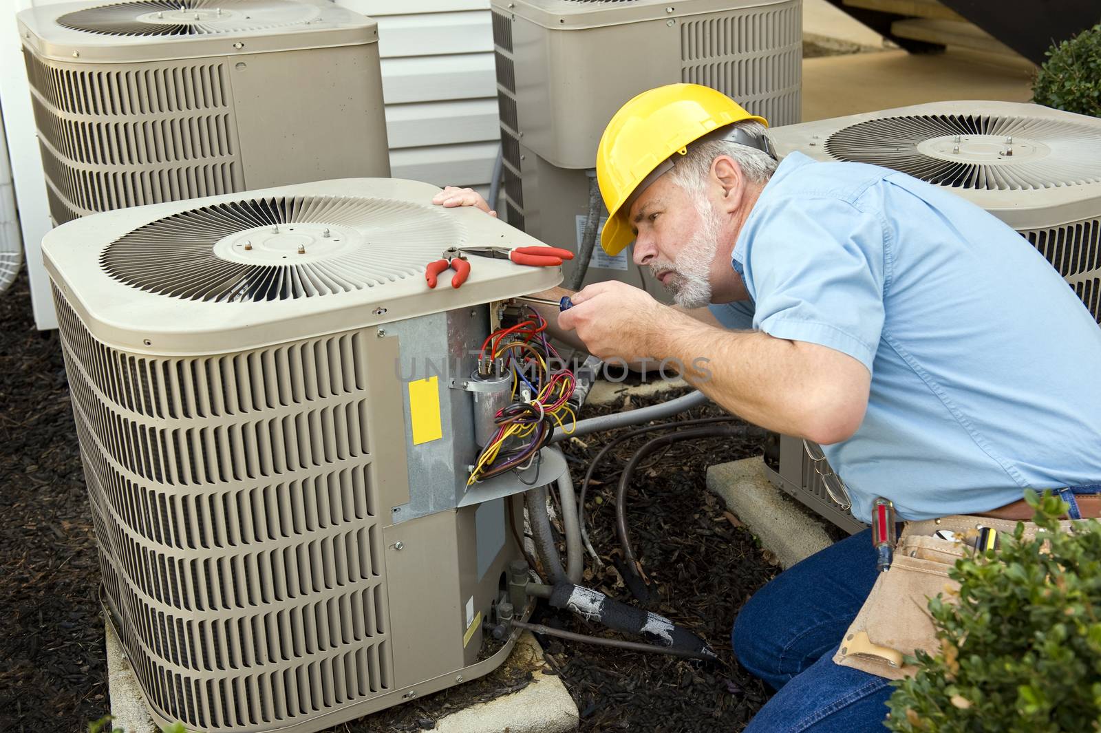 Worker repairing air conditioning unit at apartment complex