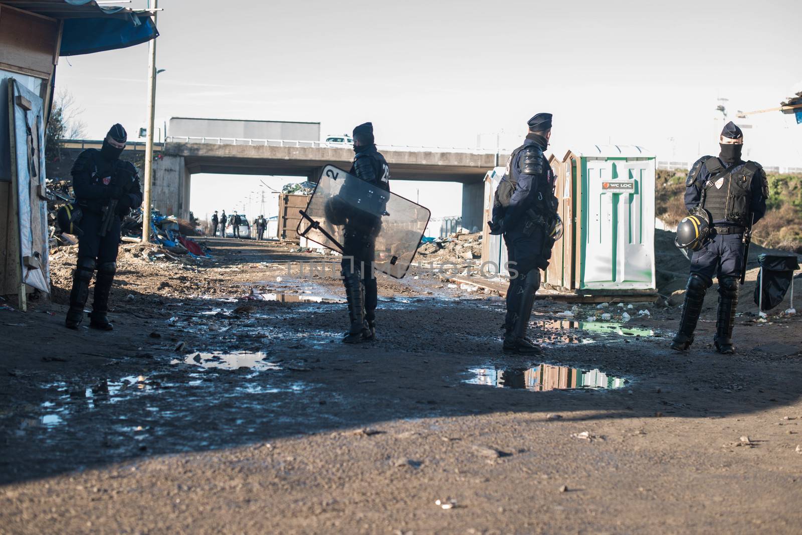 FRANCE, Calais: French riot police patrol on January 25, 2016, in a zone where makeshift shelters were cleared from in the migrant shantytown on the outskirts of Calais known as the Jungle, where thousands are trying to make their way across the English Channel.A prefectoral decree posted on January 19, 2016, gave people 24 hours to leave the premises of a 100-metre-wide strip of land in the jungle, where several small food businesses and restaurants had been set up, before its evacuation and destruction.