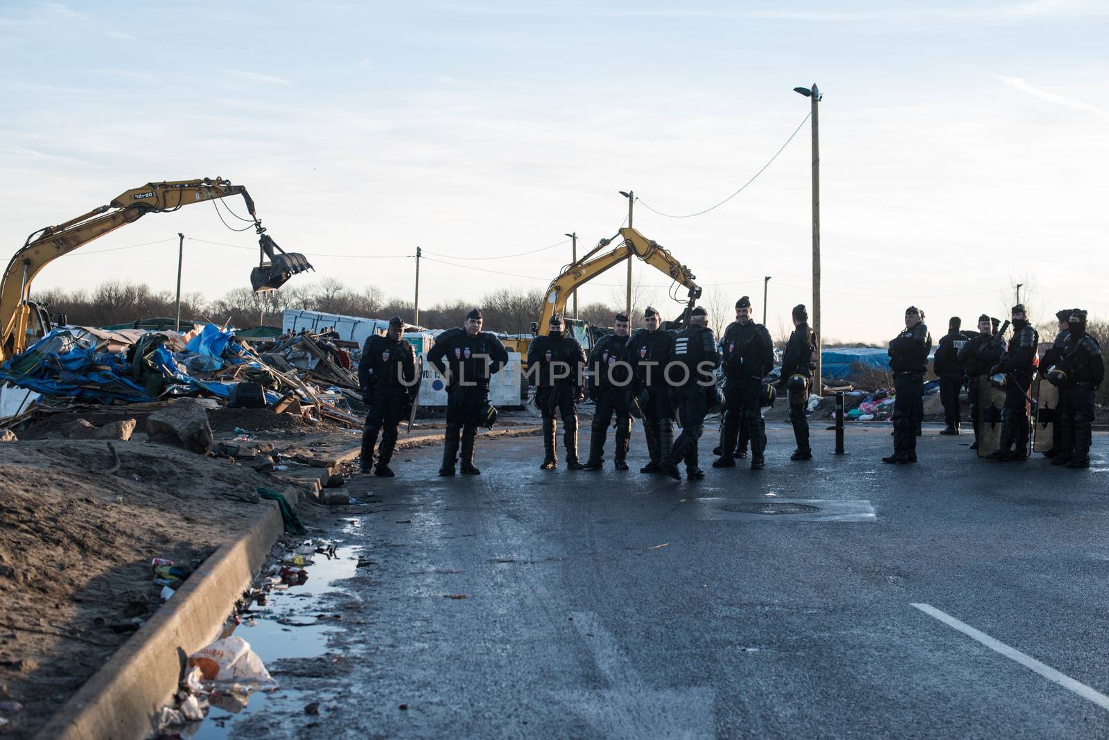 FRANCE, Calais: French riot police patrol on January 25, 2016, in a zone where makeshift shelters were cleared from in the migrant shantytown on the outskirts of Calais known as the Jungle, where thousands are trying to make their way across the English Channel.A prefectoral decree posted on January 19, 2016, gave people 24 hours to leave the premises of a 100-metre-wide strip of land in the jungle, where several small food businesses and restaurants had been set up, before its evacuation and destruction.