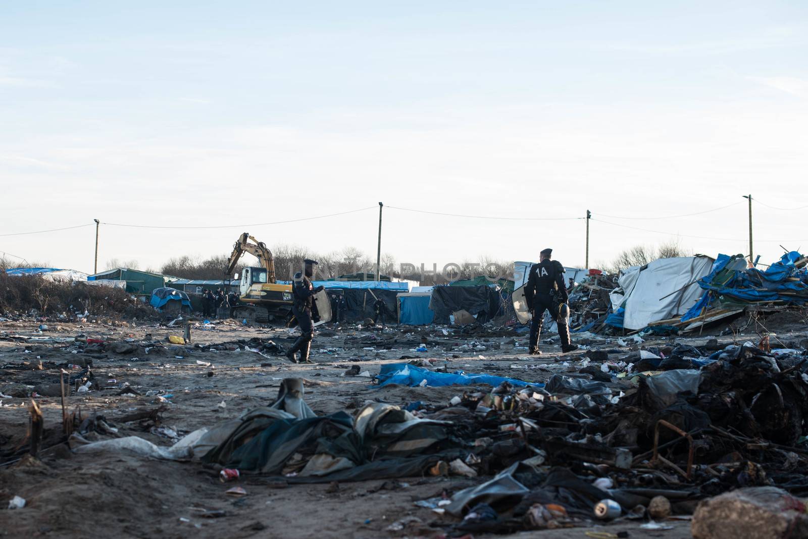 FRANCE, Calais: French riot police patrol on January 25, 2016, in a zone where makeshift shelters were cleared from in the migrant shantytown on the outskirts of Calais known as the Jungle, where thousands are trying to make their way across the English Channel.A prefectoral decree posted on January 19, 2016, gave people 24 hours to leave the premises of a 100-metre-wide strip of land in the jungle, where several small food businesses and restaurants had been set up, before its evacuation and destruction.