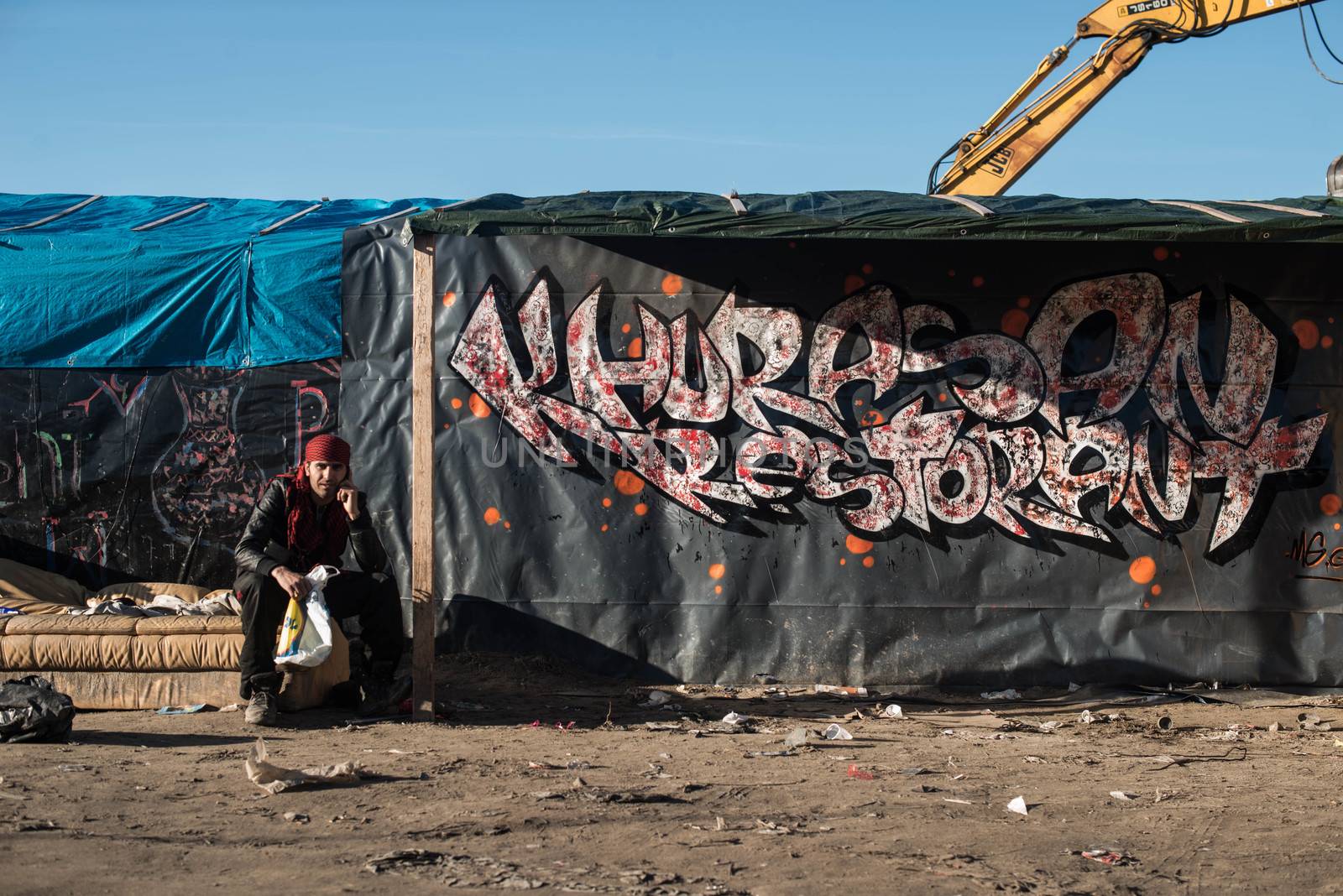 FRANCE, Calais: A migrant living the 'jungle', an encampment made up of migrants who are mainly trying to reach Britain, speaks on his mobile phone, near the French port city of Calais, northern France, on January 25, 2016.A prefectoral decree posted on January 19, 2016, gave people 24 hours to leave the premises of a 100-metre-wide strip of land in the jungle, where several small food businesses and restaurants had been set up, before its evacuation and destruction.