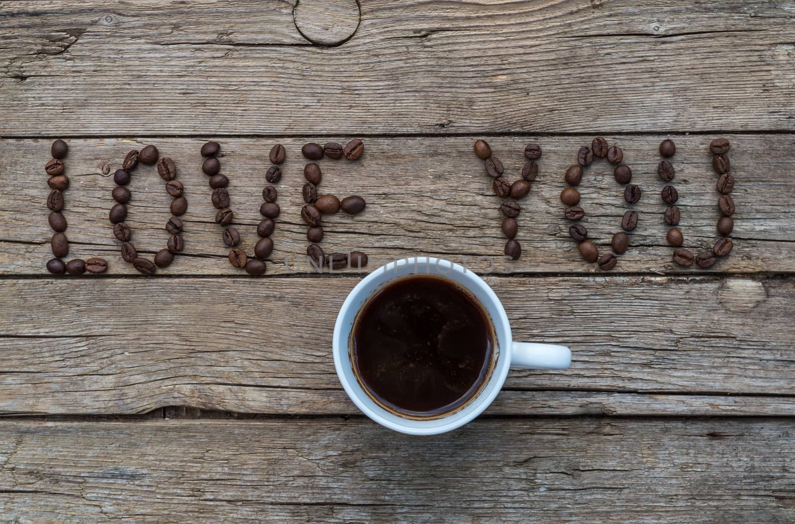 Cup of coffee on wooden background and LOVE YOU coffee beans