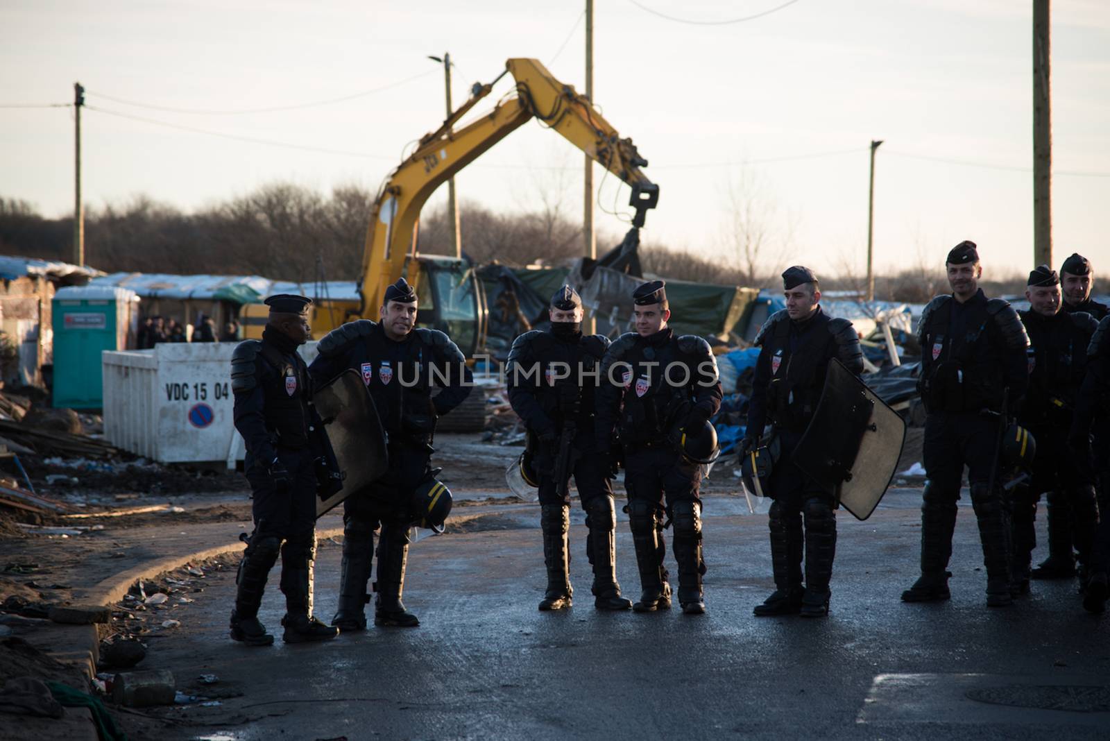 FRANCE, Calais: Policemen stand as bulldozers demolish part of the Jungle in Calais, northern France on January 25, 2016.
