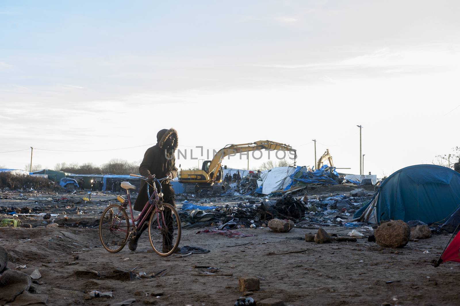 FRANCE, Calais: A migrant walks along his bike in empty parts of the Jungle in Calais after its demolition by bulldozers on January 25, 2016.