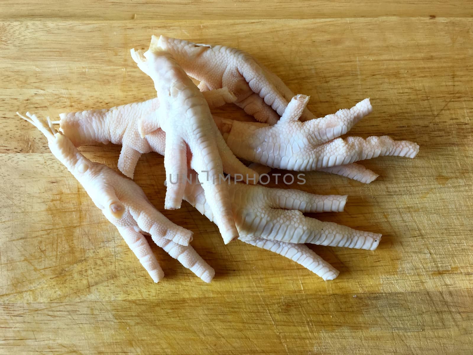 Chicken feet without toenails on a cutting board.