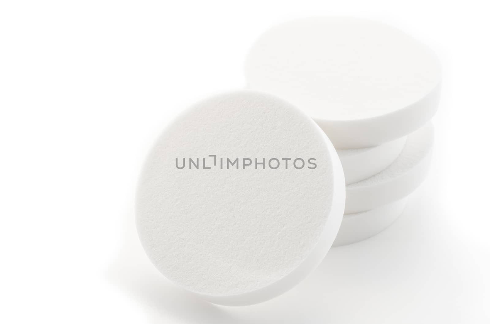 Cosmetic white circle sponges on white background.