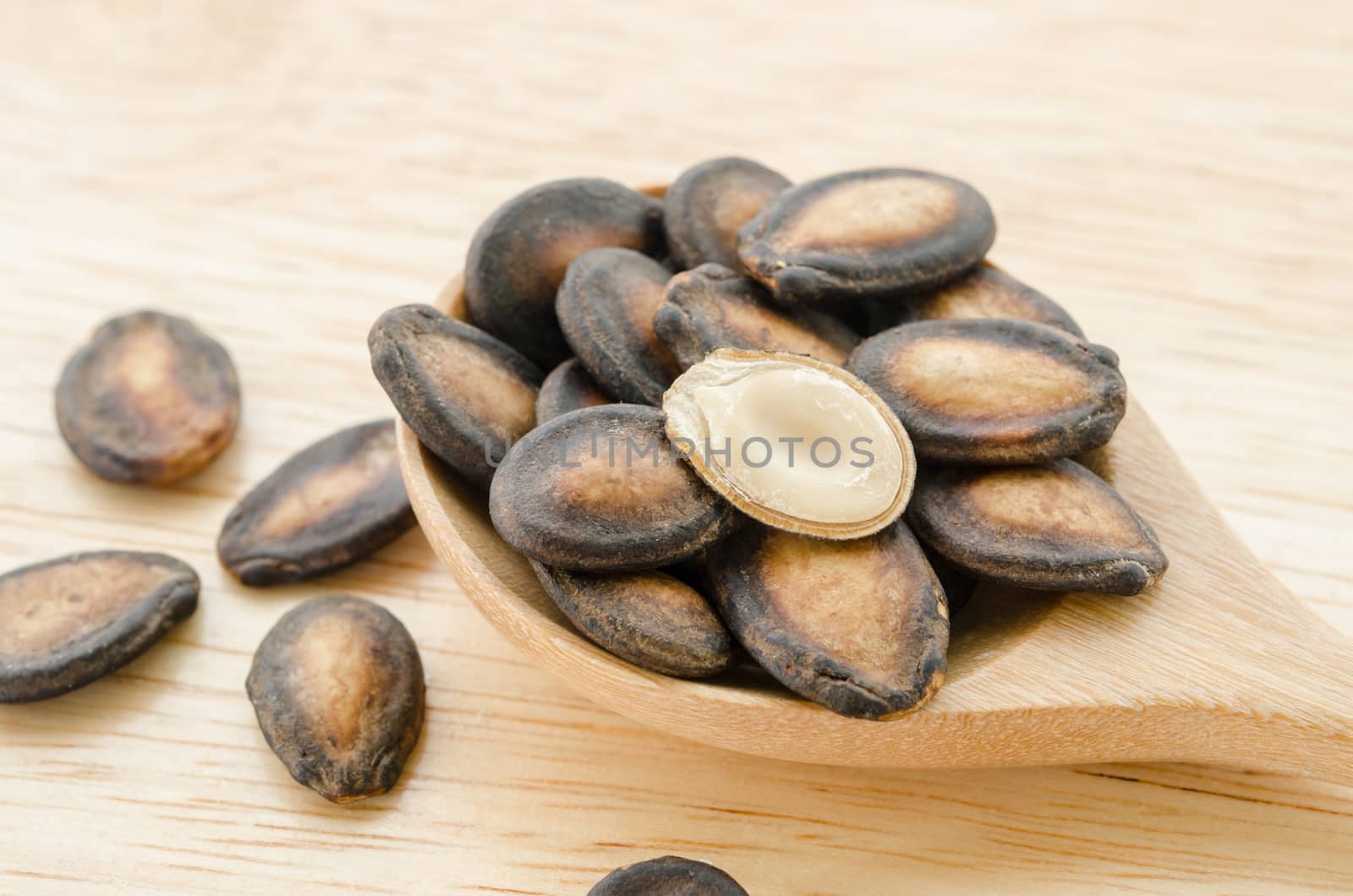 Watermelon seeds in wooden spoon on wood background