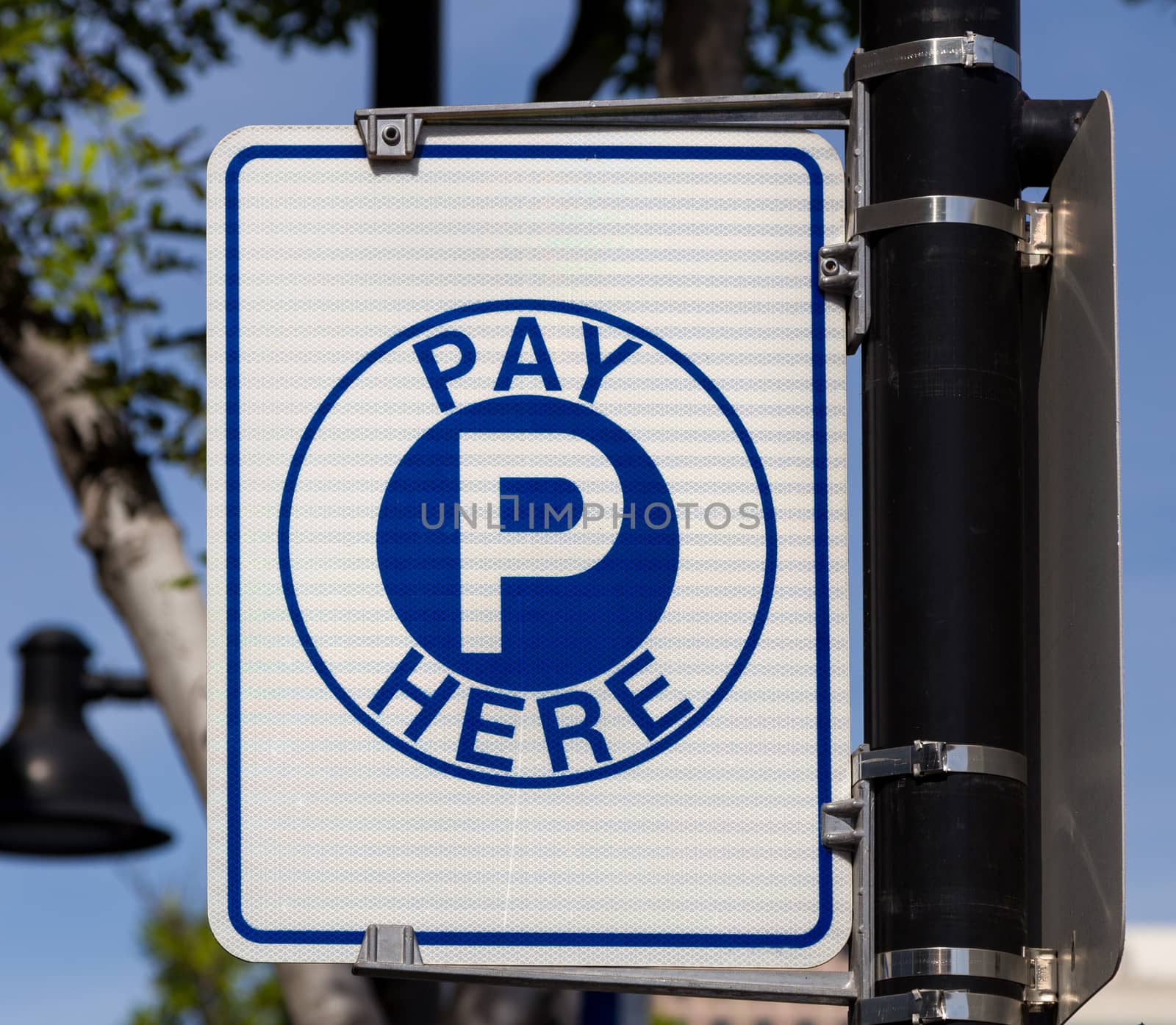Municipal parking meter sign with blue letter on white background.