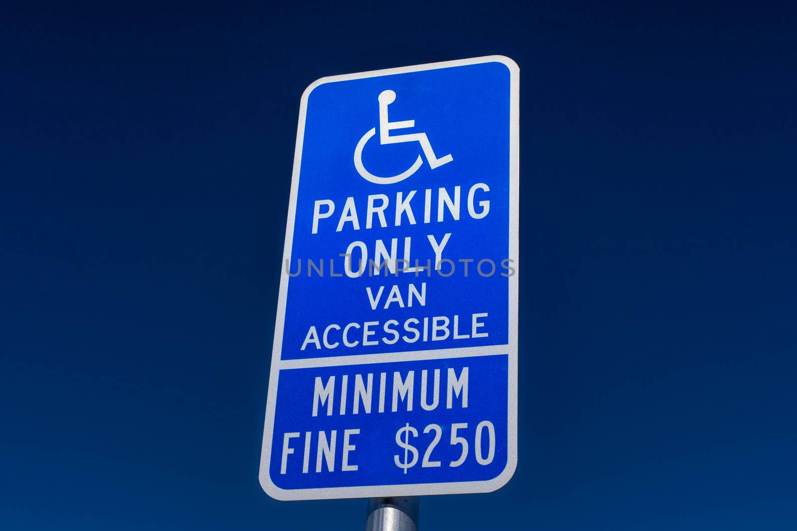 Handicapped parking sign with white lettering on blue backdrop.