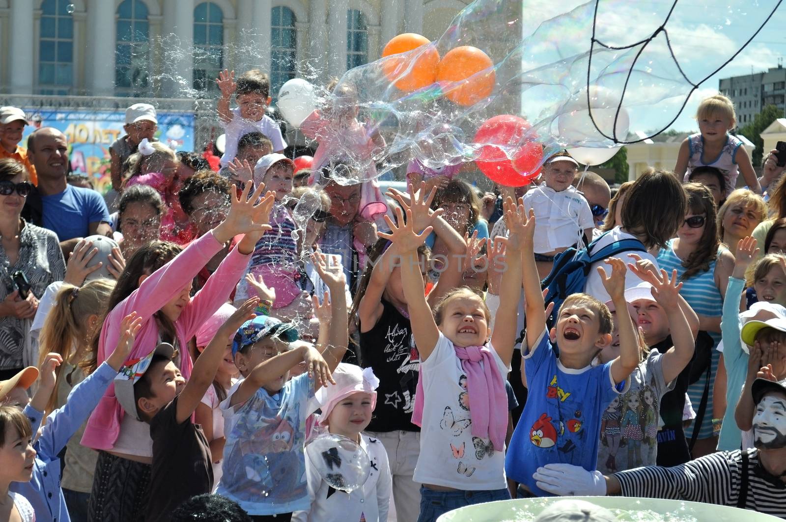 Happy children catch soap bubbles on the square at Dramatic thea by veronka72