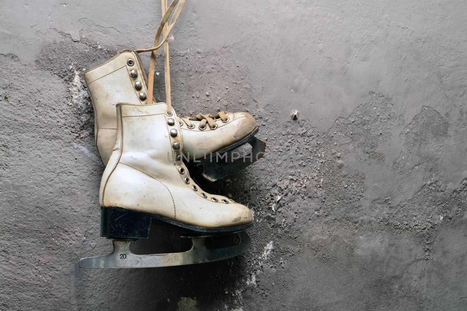 Women ice skates hanging on gray cement background