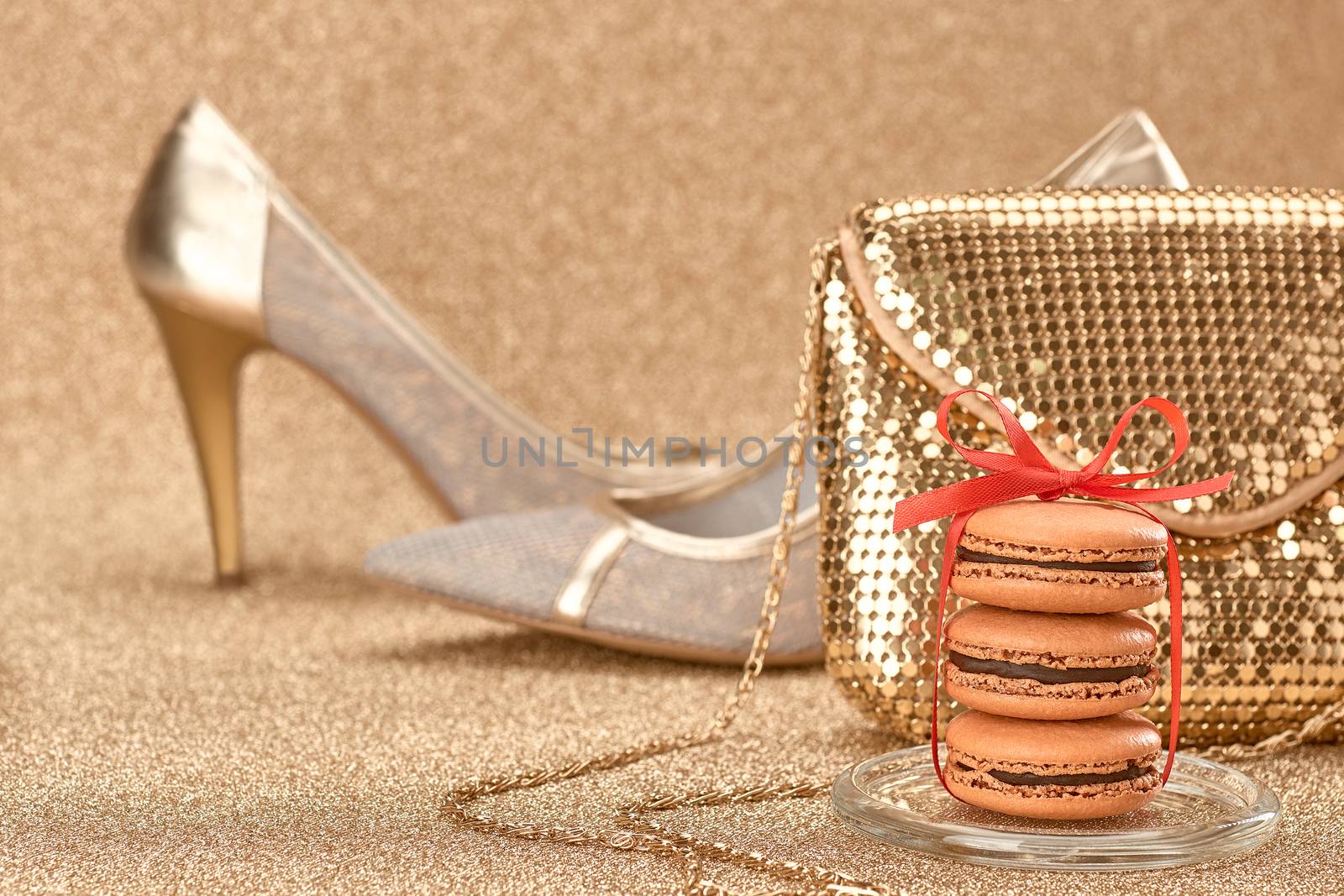 Macarons french dessert, Luxury shiny shoes high heels, glamor fashion handbag clutch, red ribbon. Vintage retro romantic style. Unusual creative art greeting card, gold party background, bokeh