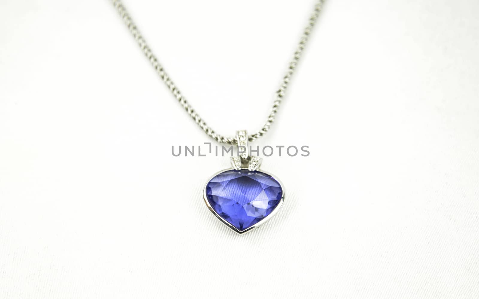 A beautiful pendant with a blue gemstone on the silver neckless isoalted on white studio background.