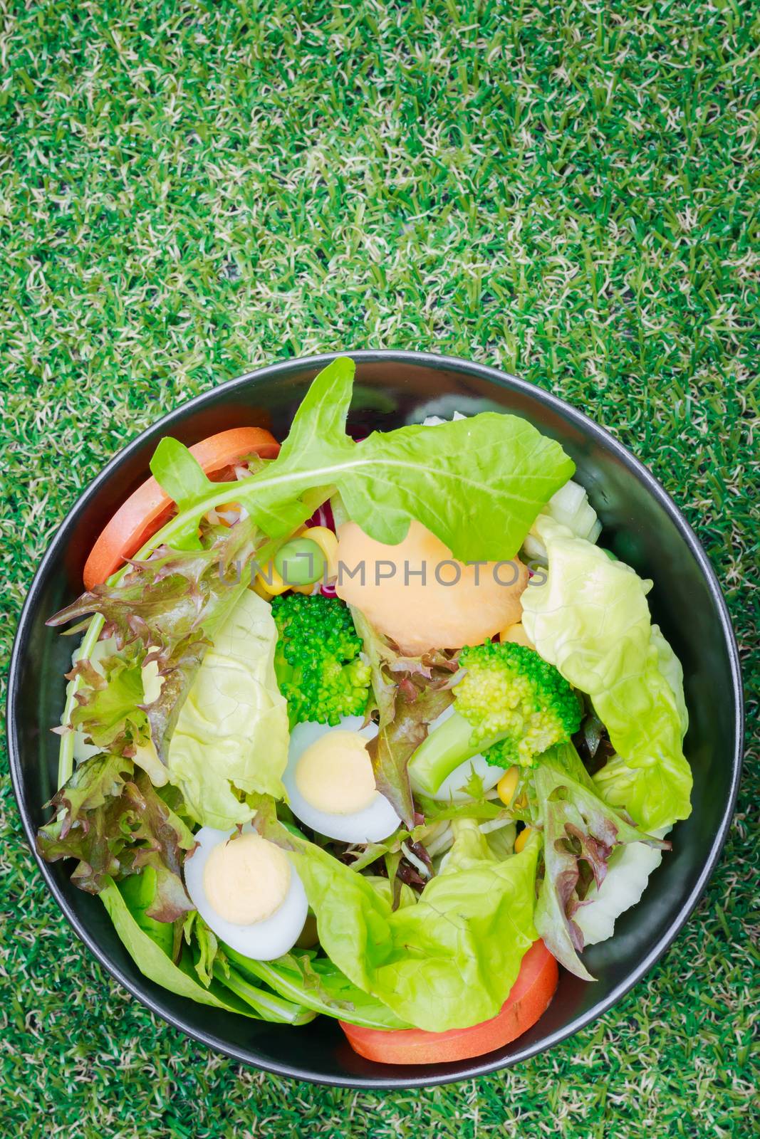 Mixed salad with quail eggs on green grass