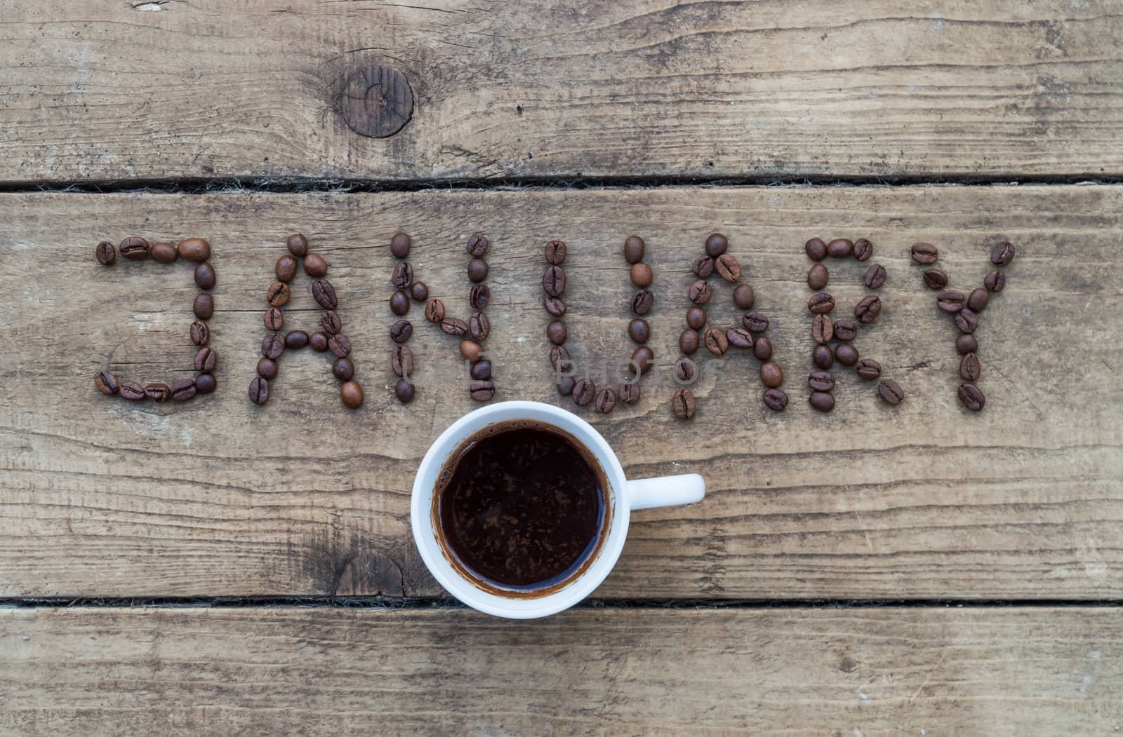 Cup of coffee on wooden background and January coffee beans