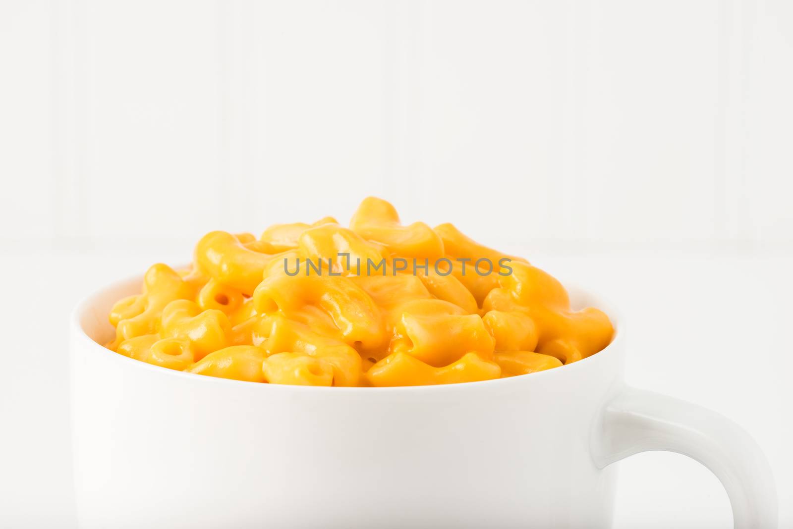 Closeup of creamy macaroni and cheese in a mug.