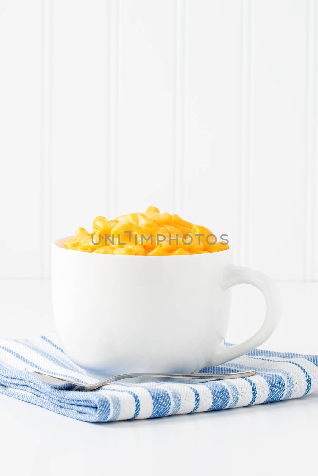 Mug filled with creamy cheddar macaroni and cheese.