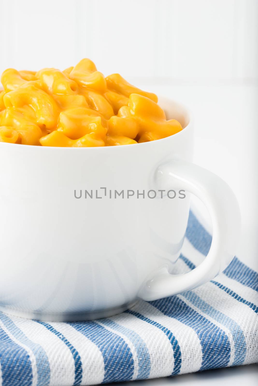Creamy macaroni and cheese in a mug photographed closeup.