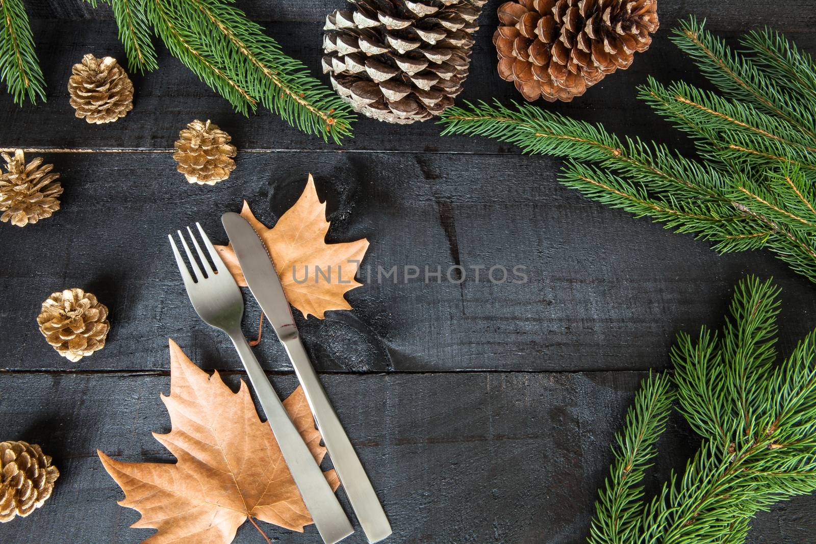 Composition of cutlery on wood background for branches and a decorative dry oranges, pain fruit and leafs for informal dinners or family celebrations in autumn winter season