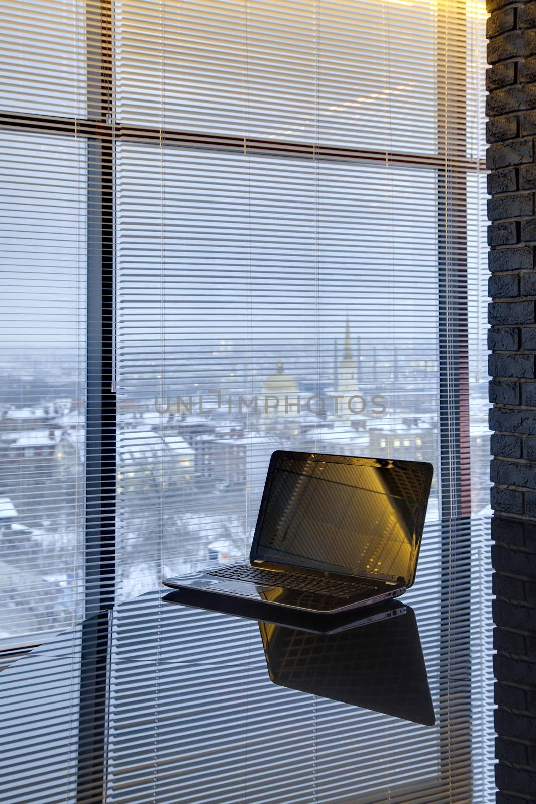 glass table with the laptop about a window in office room