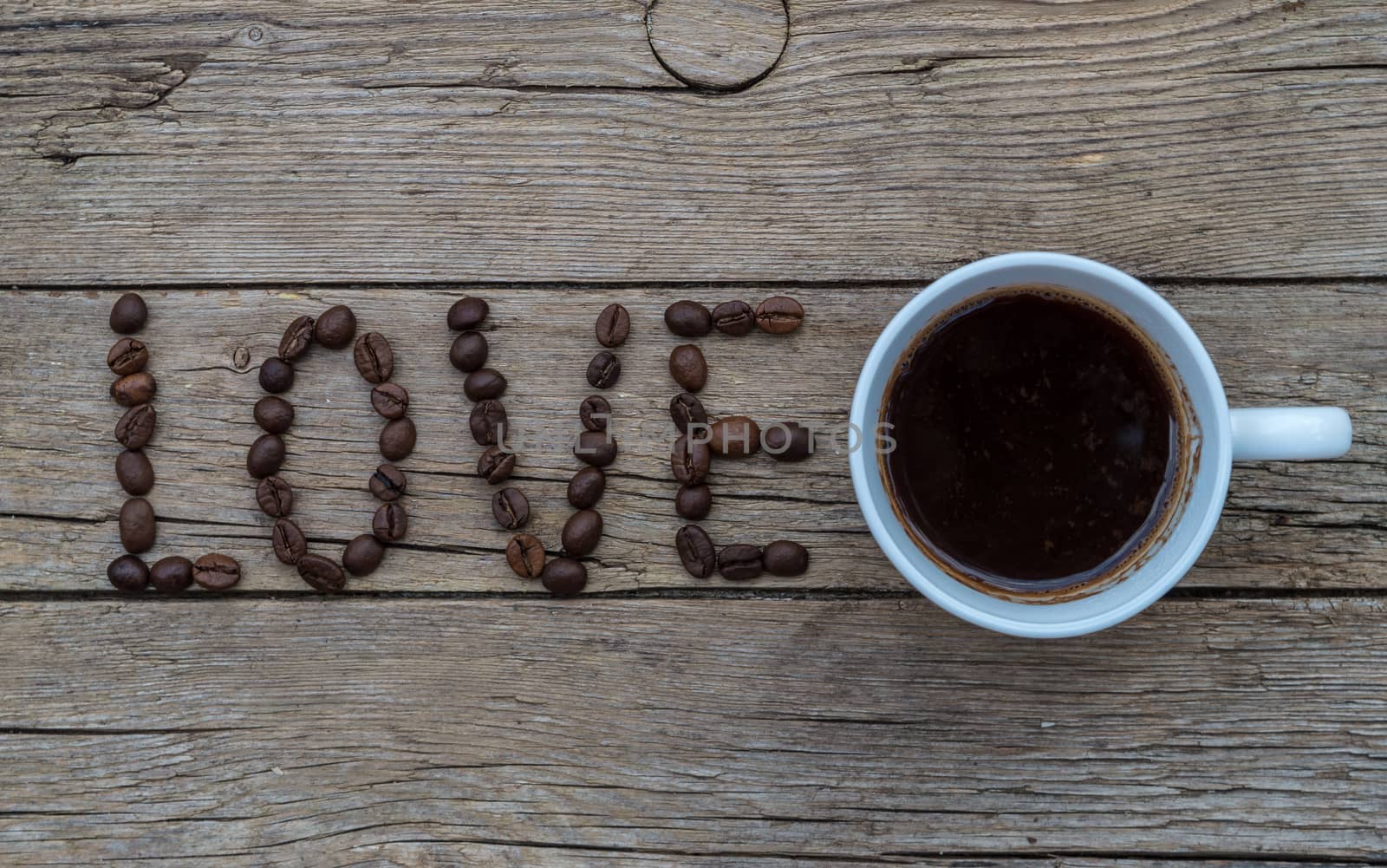 Cup of coffee on wooden background and LOVE coffee beans