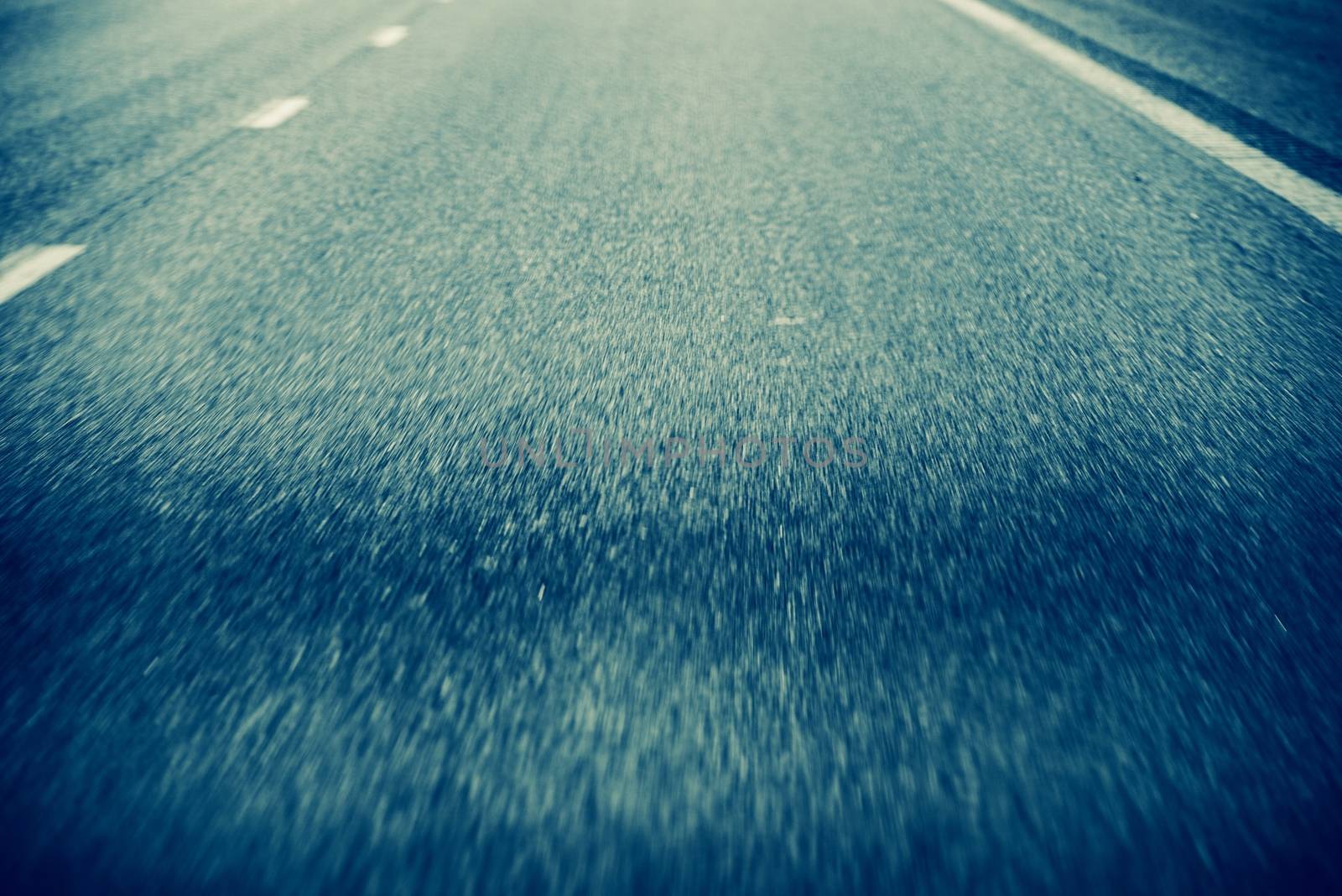 On the Road Background. Road in Motion. Pavement Closeup During Driving.