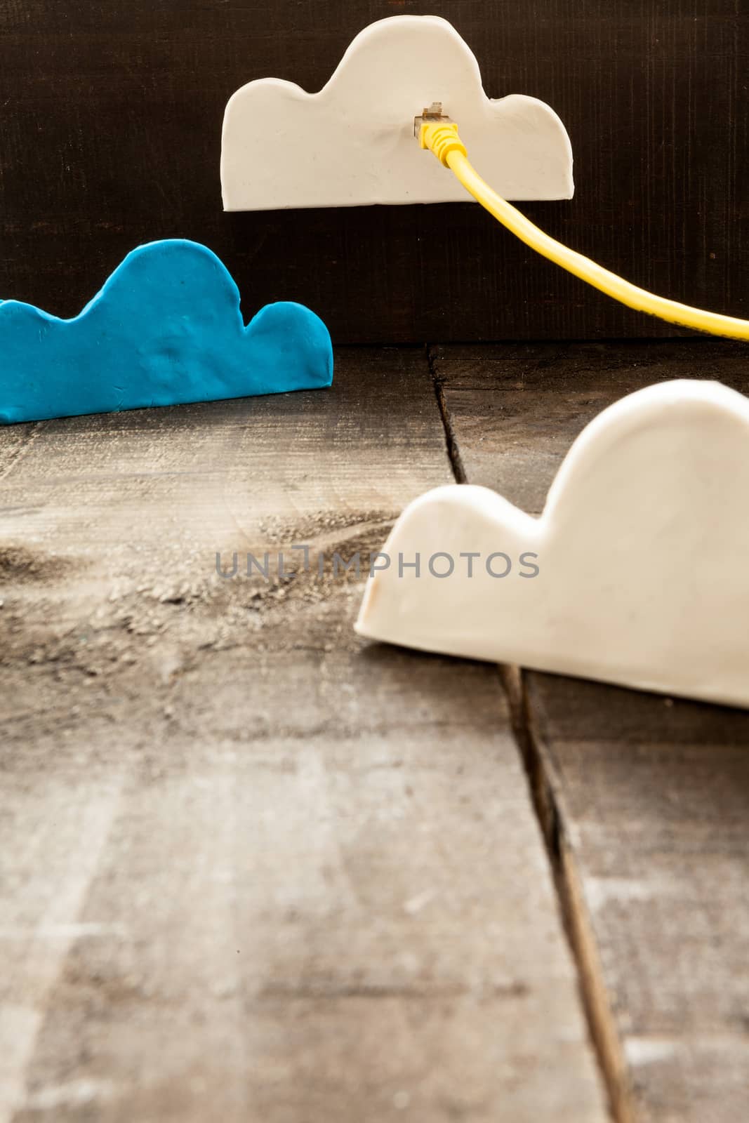 The image shows clouds of clay imitating the clouds and the concept of technological clouding over wooden background as if it were an illustration