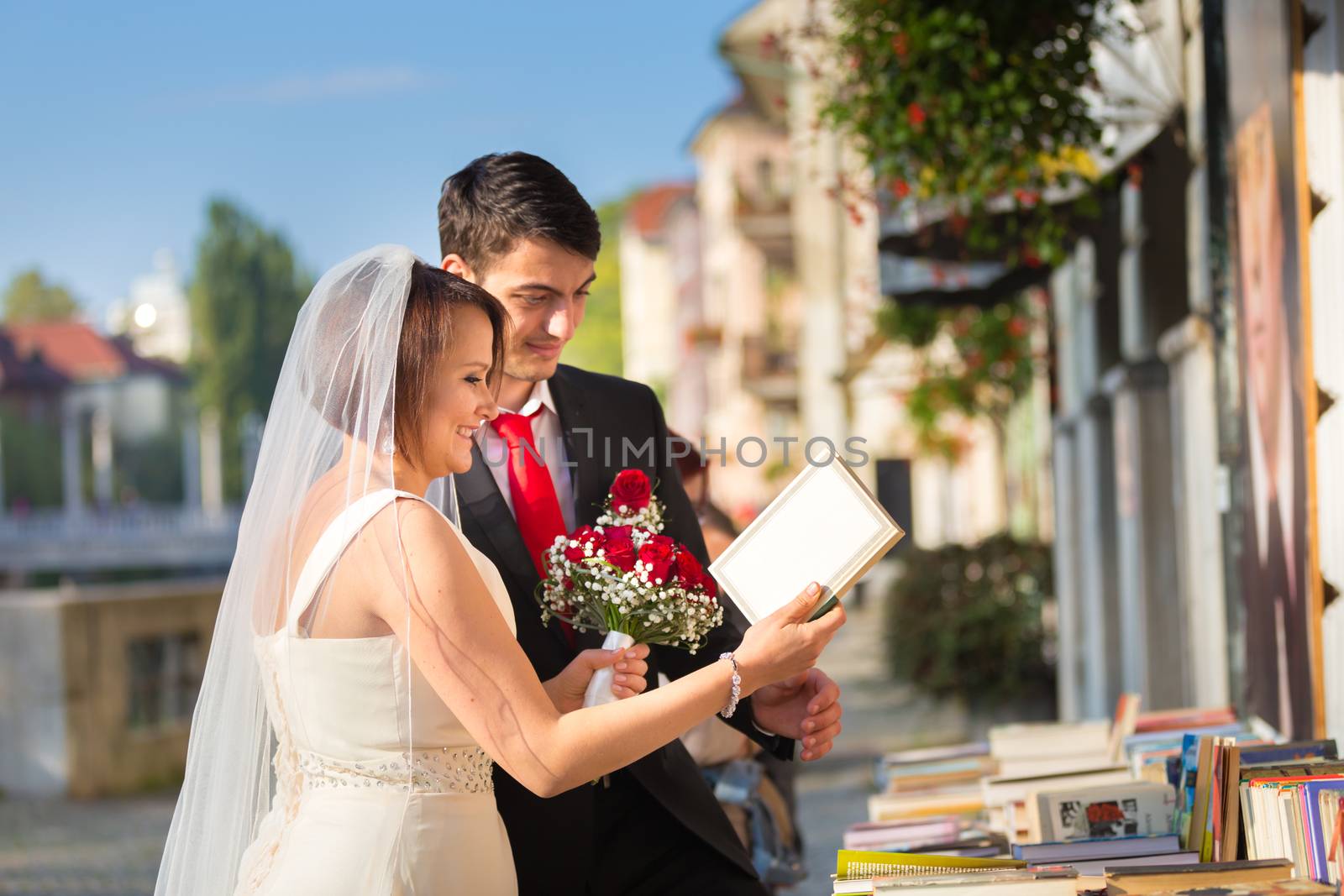 Bride and groom. Portrait of a loving wedding couple reviewing vintage books in antique book shop in medieval city center of Ljubljana, Slovenia.