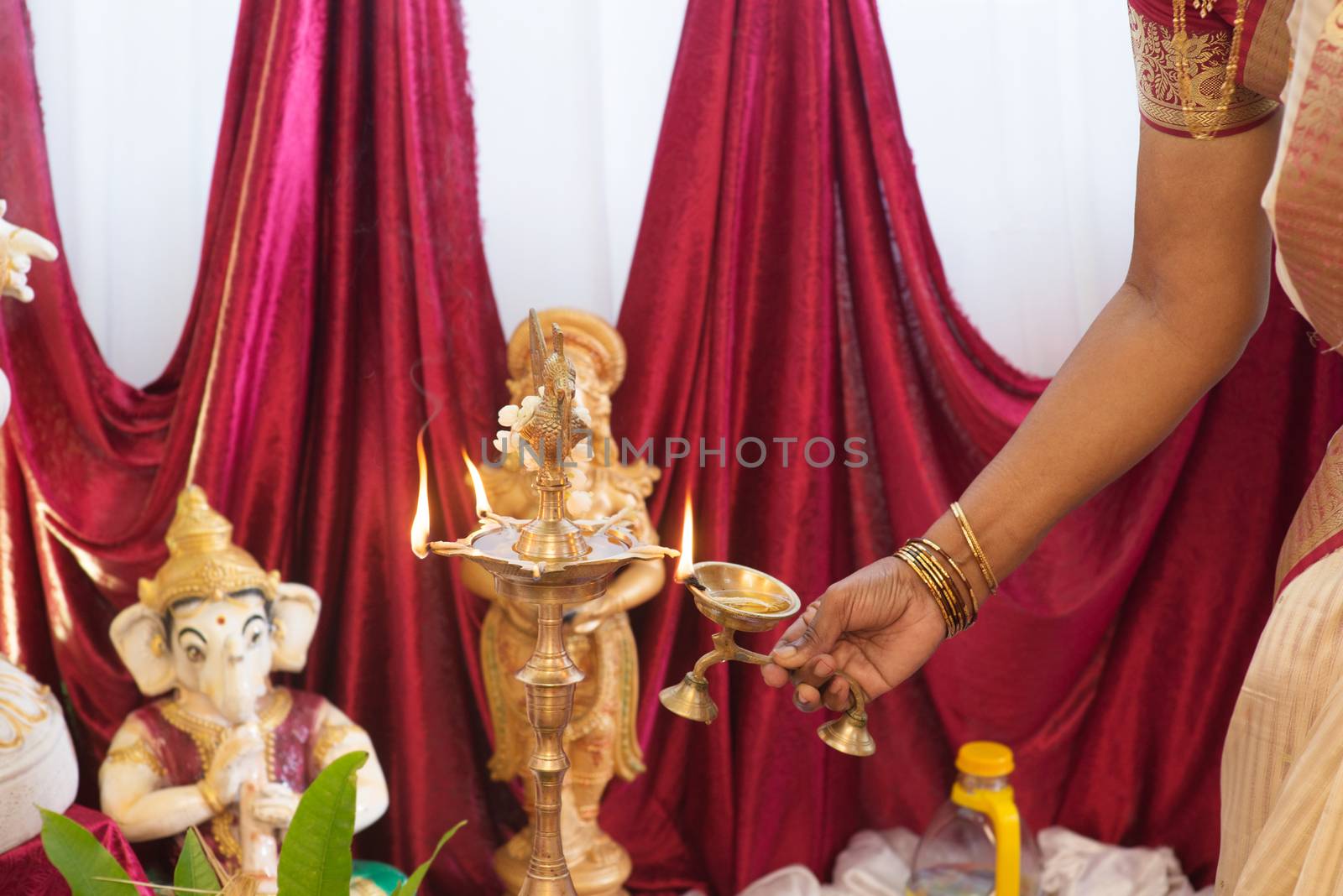 Woman hand lighting up the metal diya. Traditional Indian Hindus religious ceremony. Focus on the oil lamp. India special rituals events.