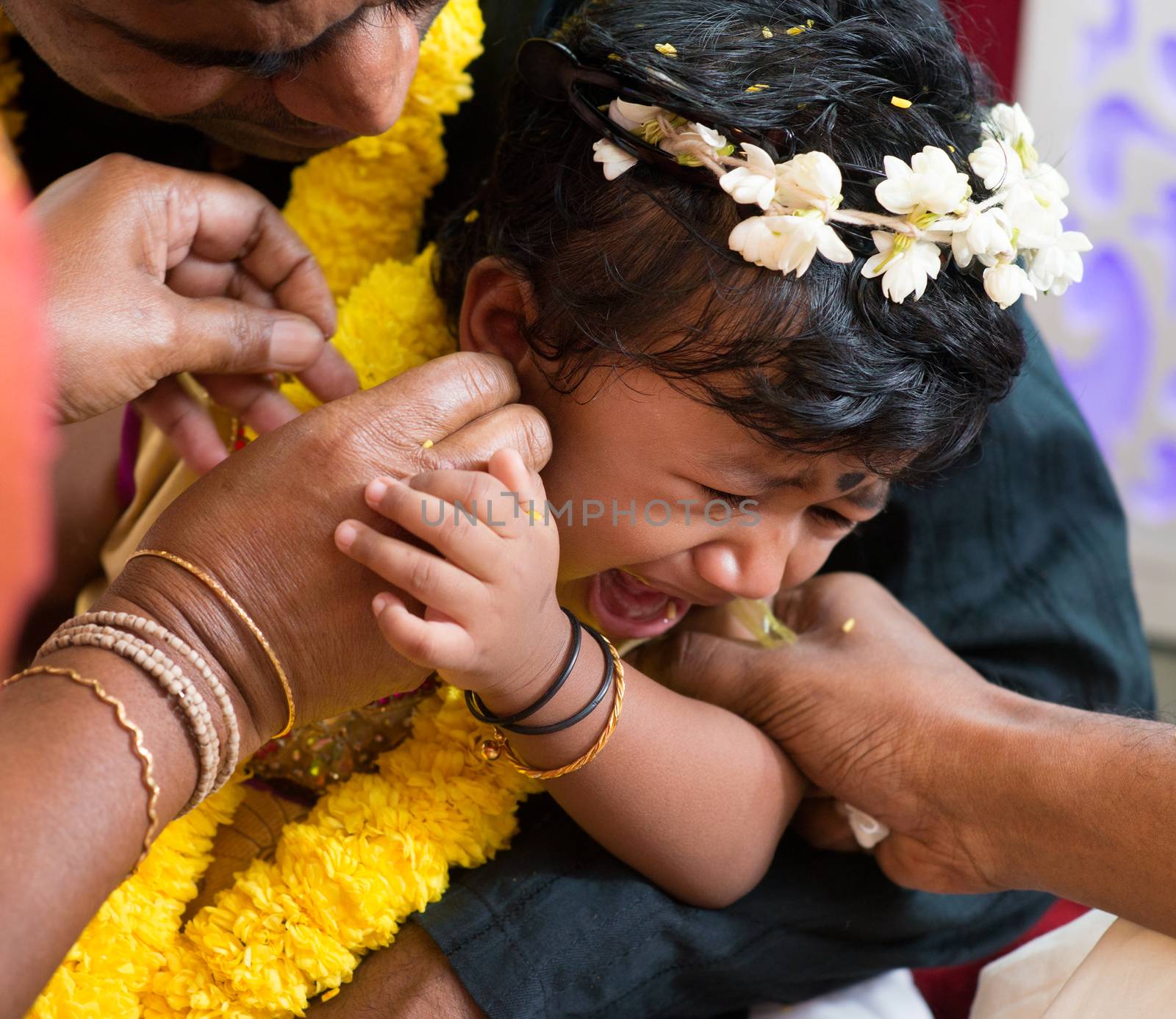 Baby girl crying during the karna vedha events. Traditional Indian Hindus ear piercing ceremony. India special rituals.