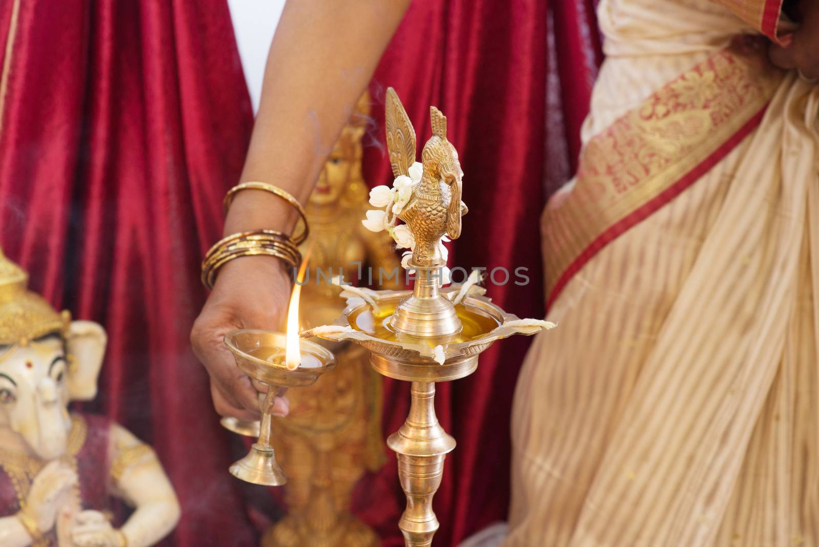 Woman lighting up the metal diya. Traditional Indian Hindus religious ceremony. Focus on the oil lamp. India special rituals events.