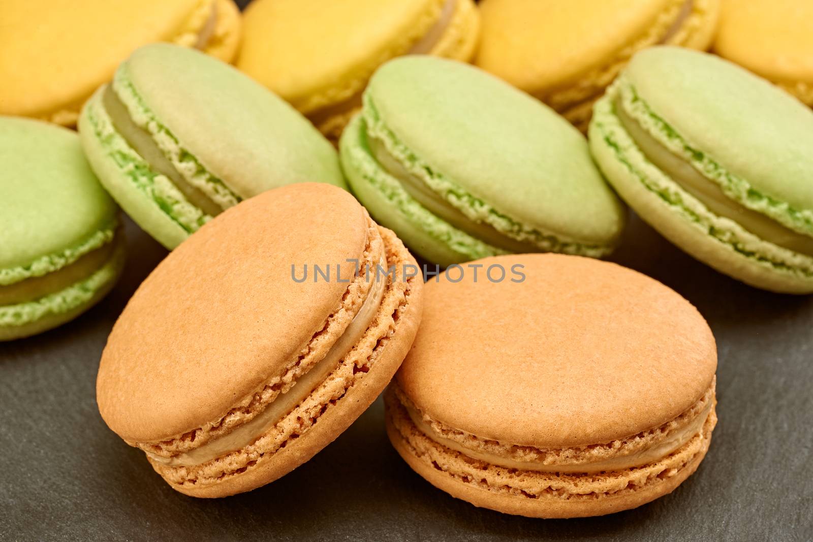 Macarons sweet colorful on black placemat. Fresh pastel french traditional delicious dessert. Unusual creative romantic, background. Food closeup