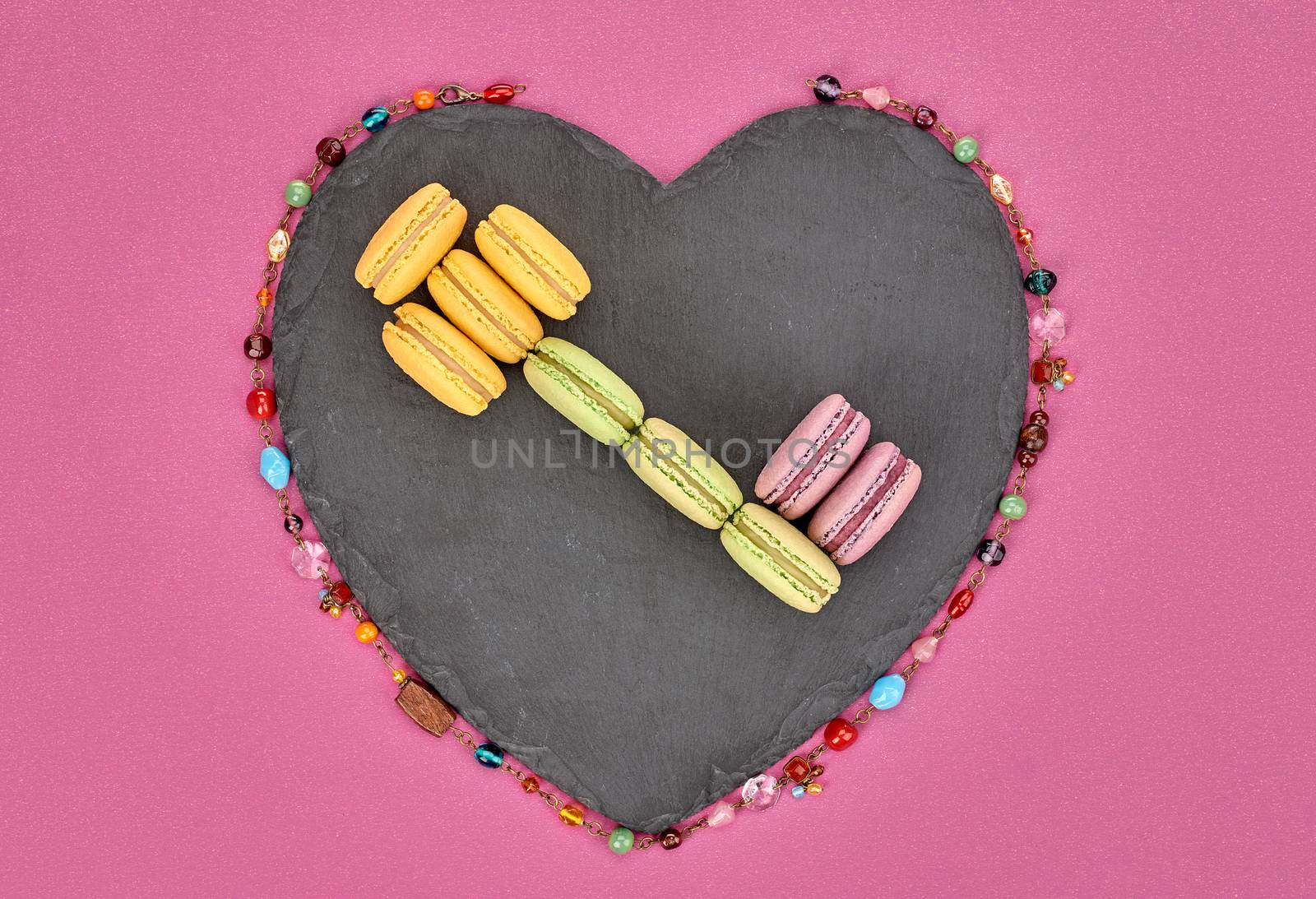 Still life, macarons sweet colorful, key shape, heart black placemat. French traditional delicious dessert, necklace. Unusual creative romantic, pink background. Concept for love story.Valentines Day