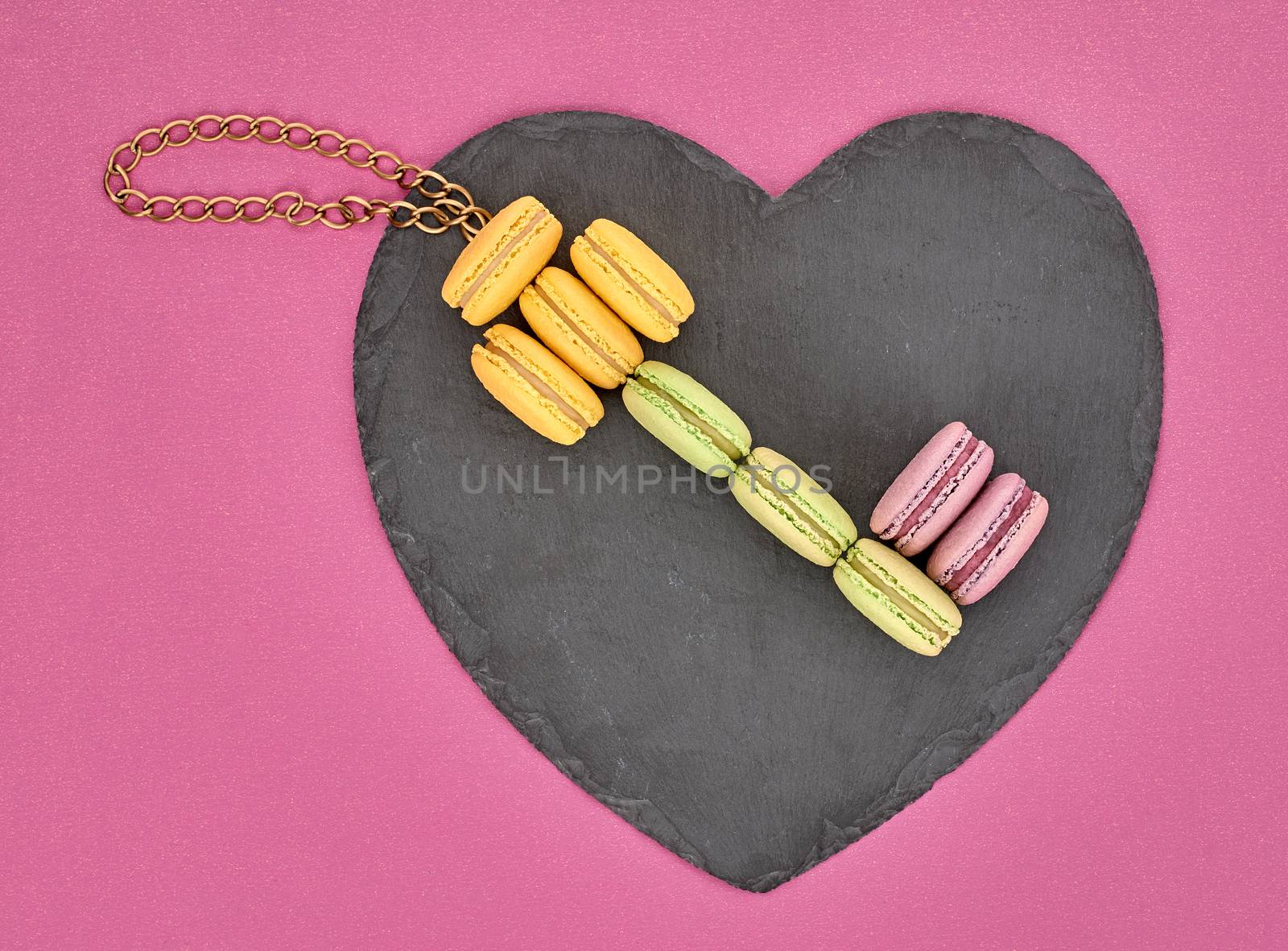 Still life, macarons sweet colorful, key shape, heart black placemat. French traditional delicious dessert with chain. Unusual creative romantic, gray background. Concept for love story.Valentines Day