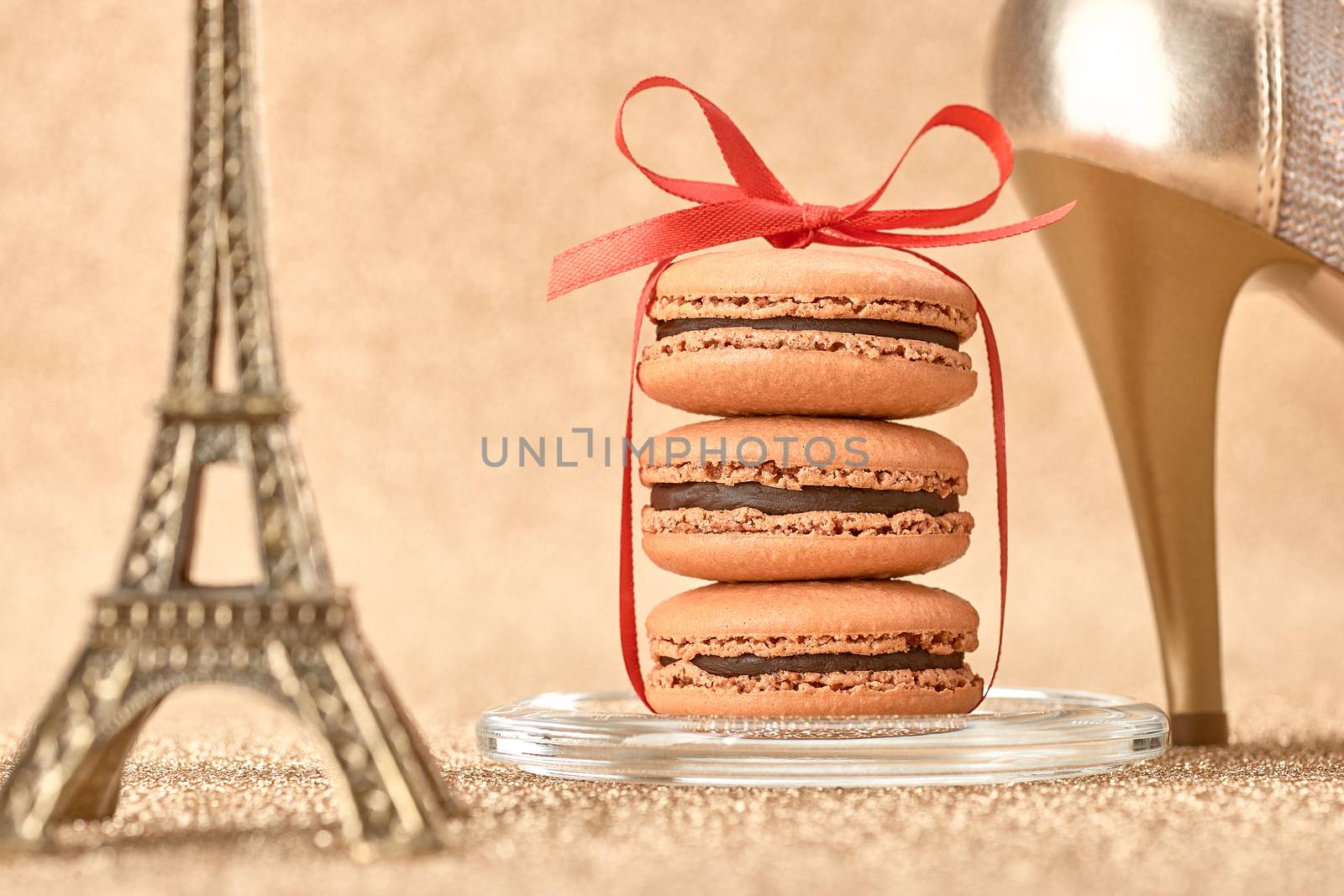 Macarons french dessert. Still life. Luxury shiny shoes high heels, Eiffel Tower, souvenir from Paris, red ribbon. Vintage retro romantic. Unusual creative art greeting card, gold background, bokeh