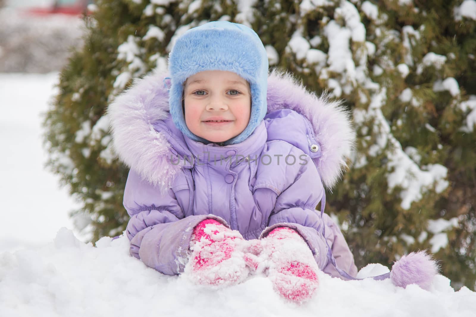 Five-year girl lies on snowdrift snow against a snowy background Trees