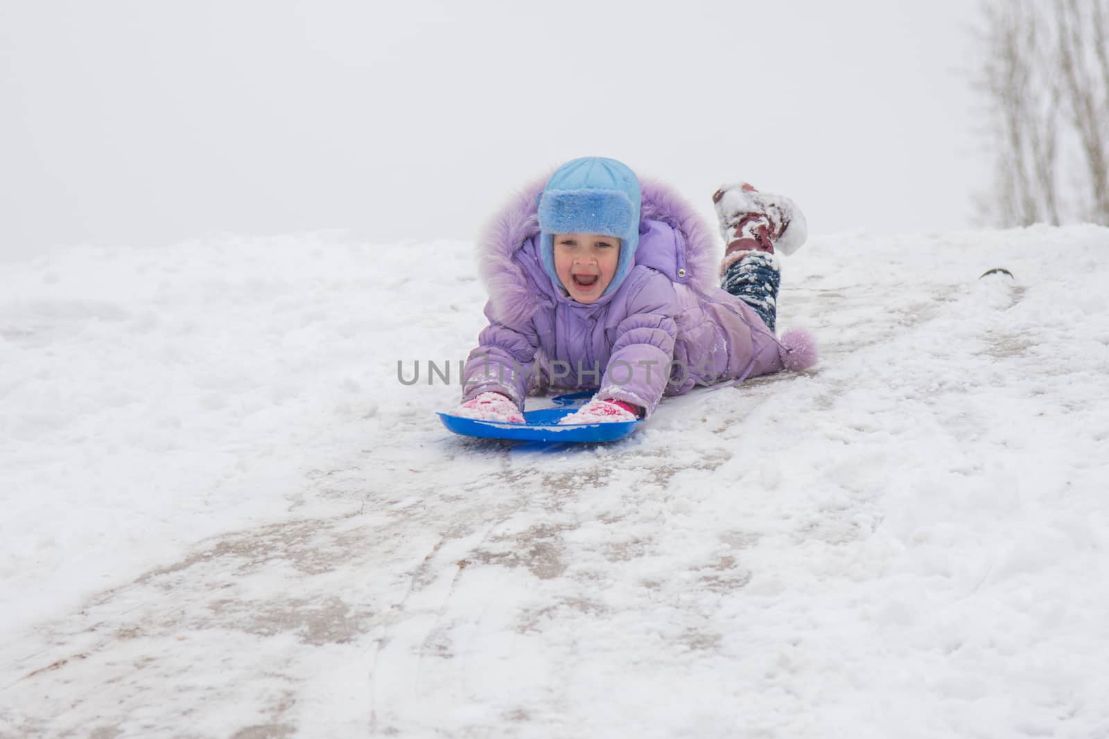 Five-year girl riding on a snowy icy hill