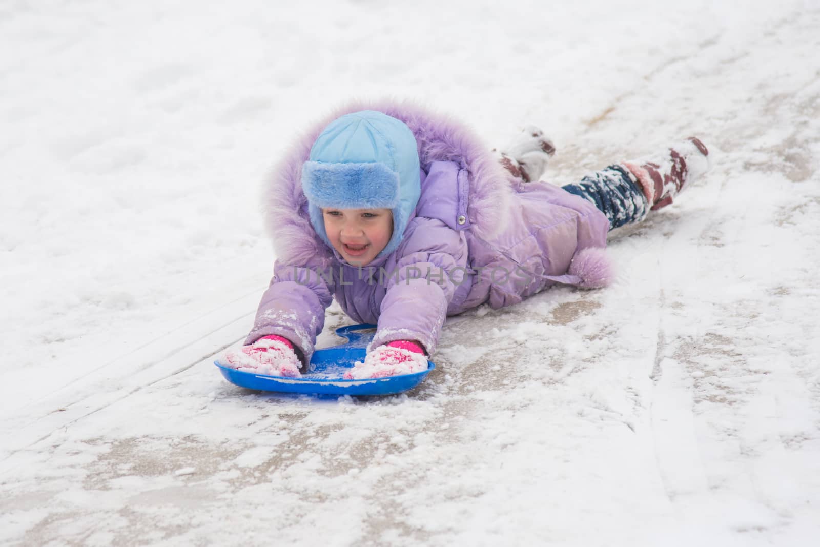 Five-year girl riding on a snowy icy hill