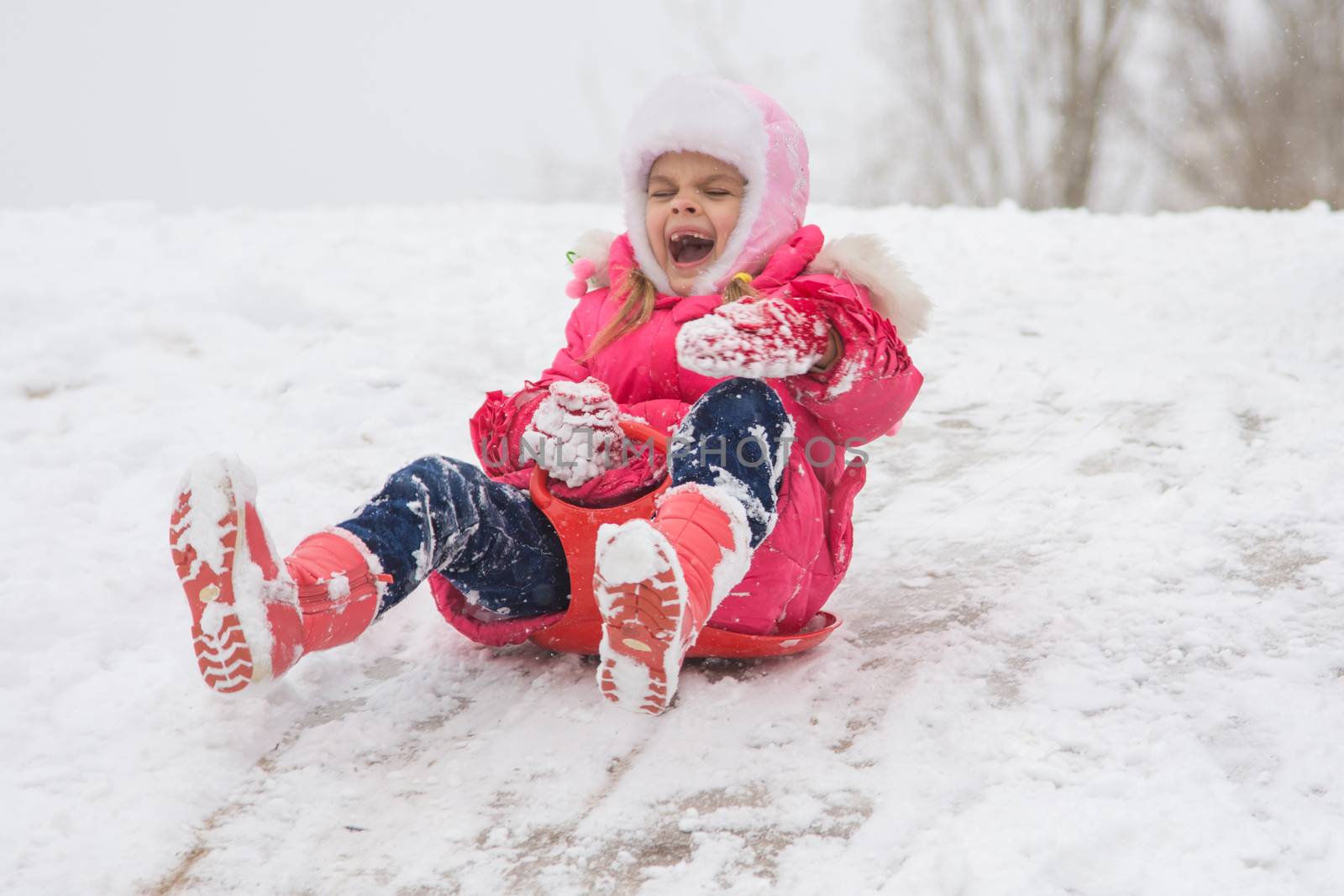 Seven-year girl riding on a snowy icy hill