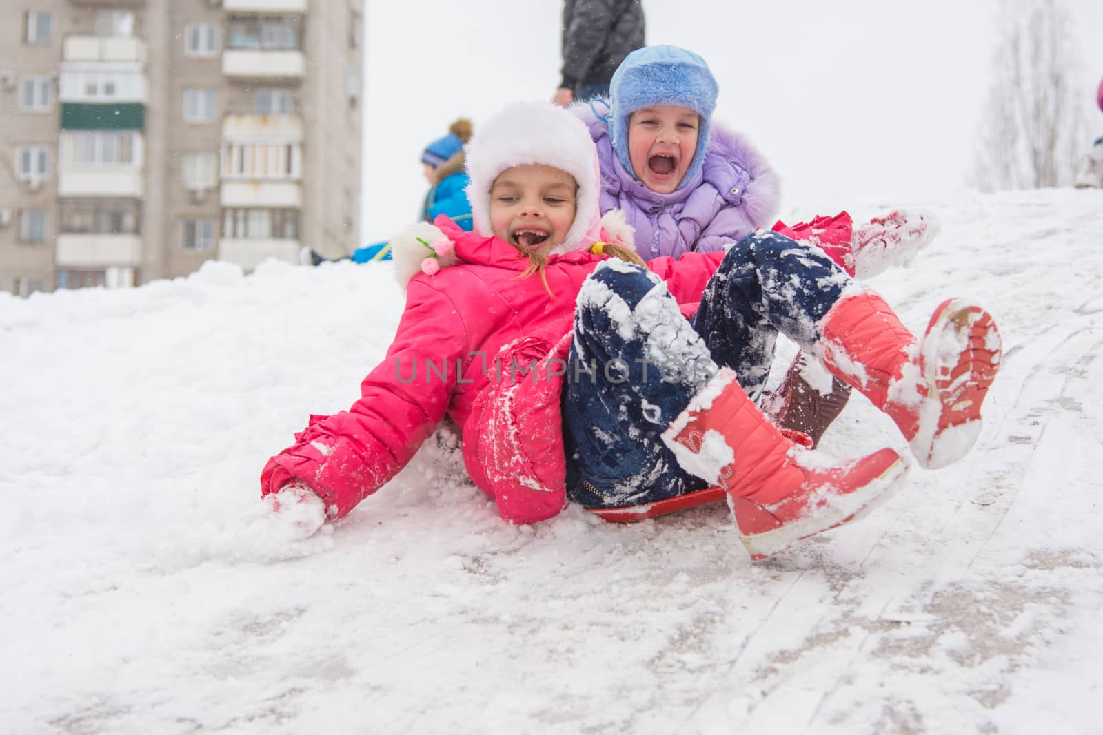 Seven-year and five-year girl riding on a snowy icy hill