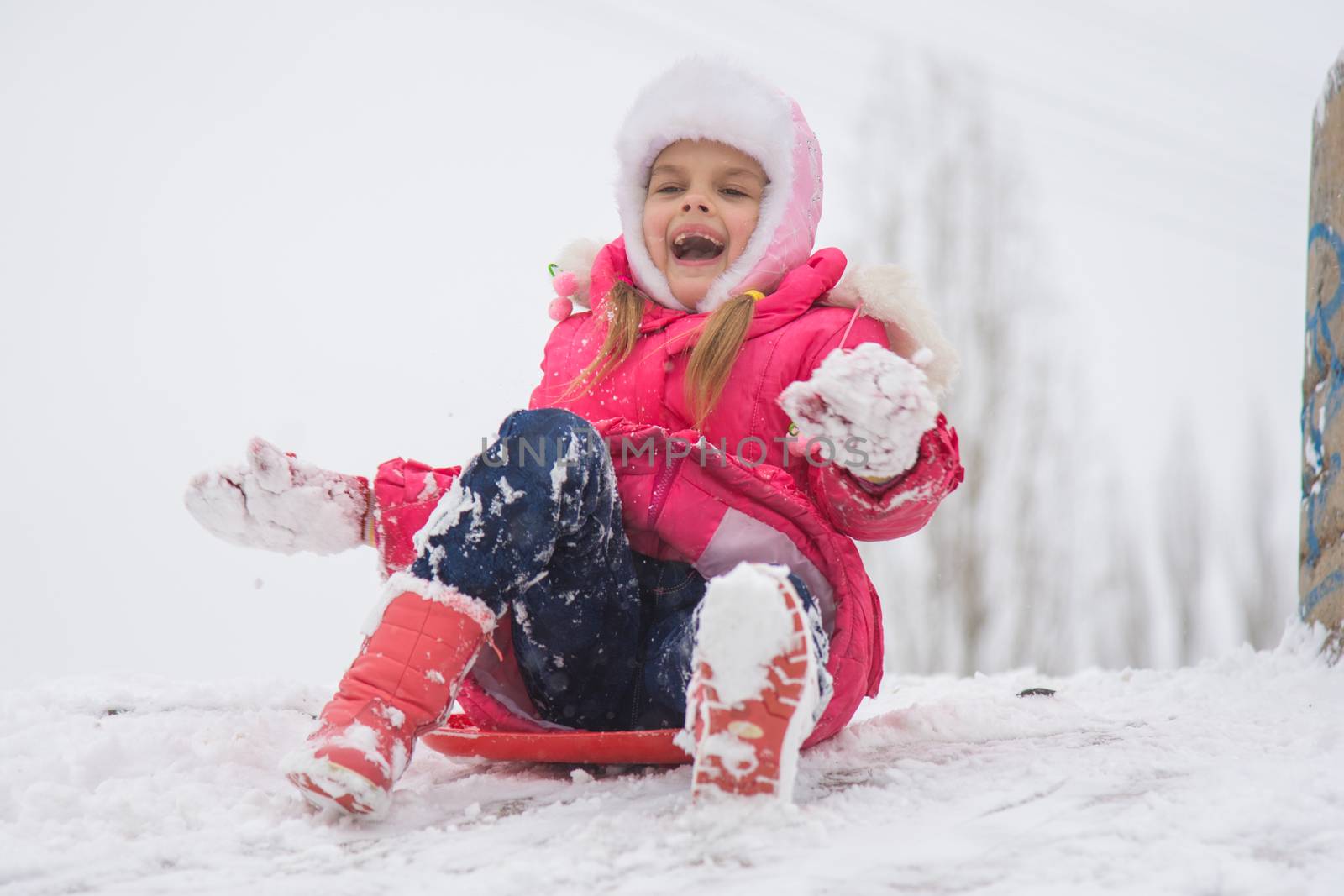 Seven-year girl riding on a snowy icy hill