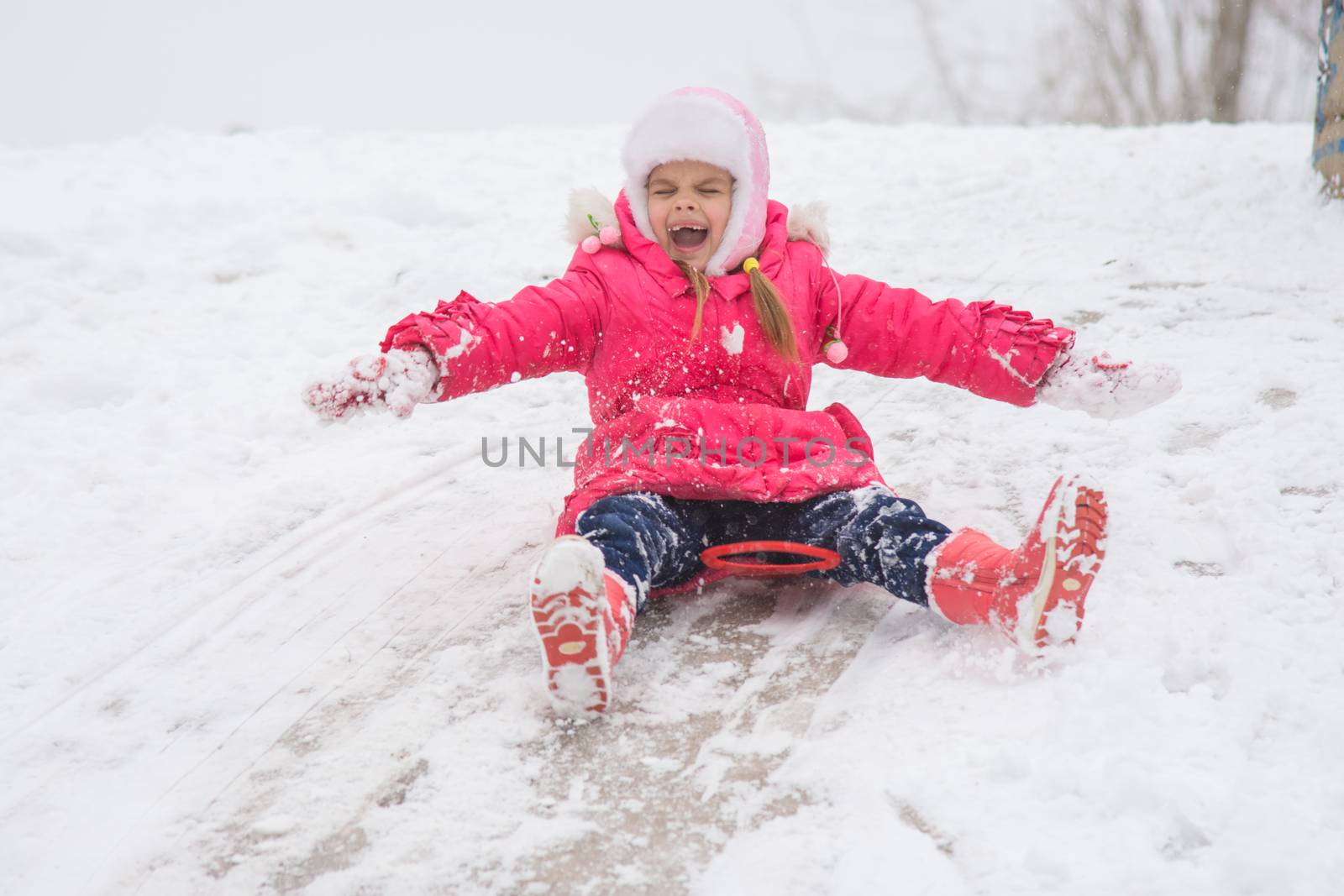 Seven-year girl riding on a snowy icy hill