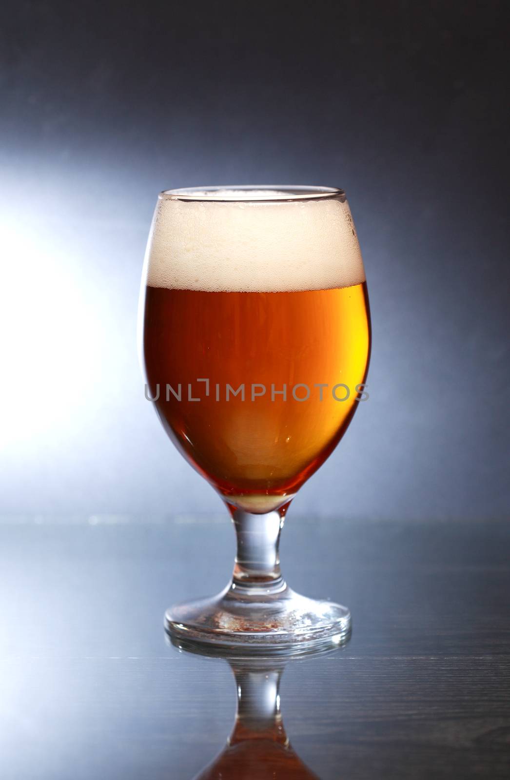 Glass of beer with foam on nice dark background