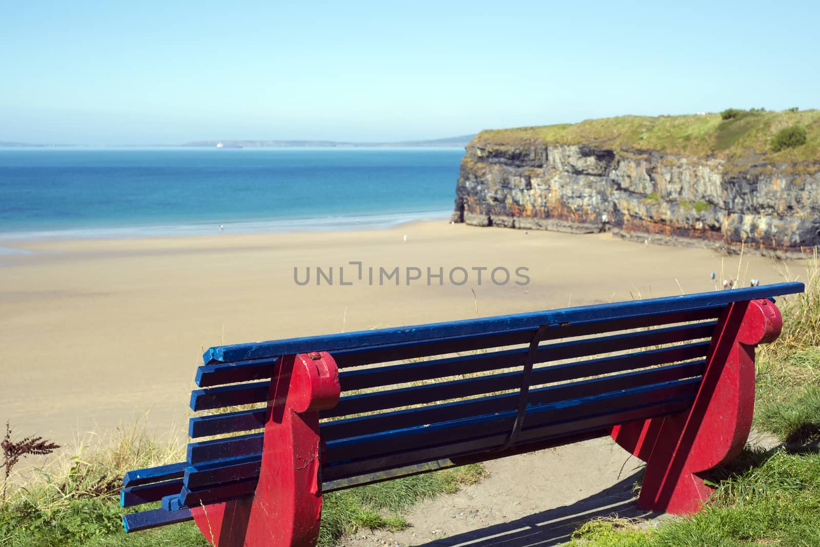 cliff walk bench overlooking the beach by morrbyte