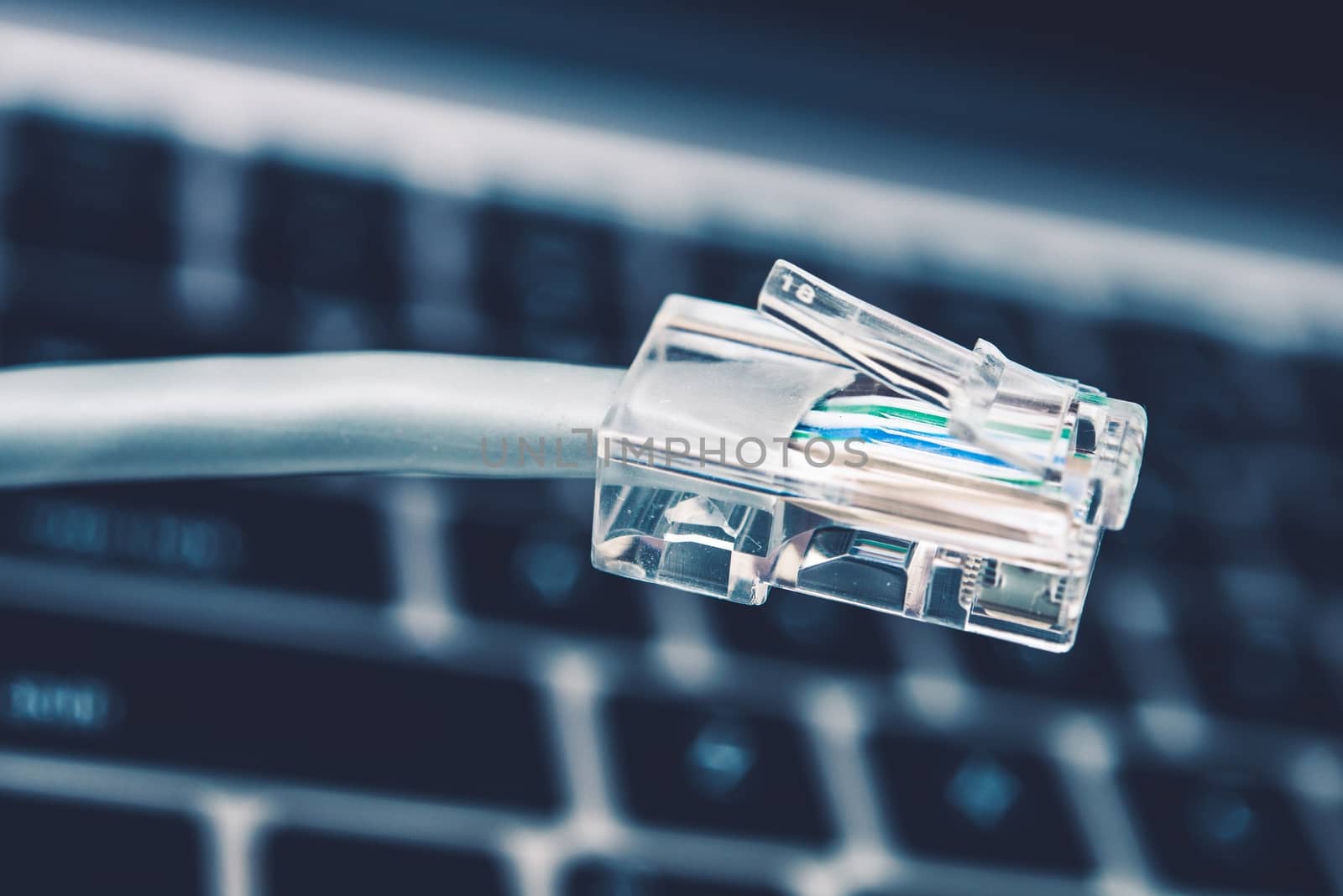 RJ45 Network Cable Connector Closeup with Keyboard in the Background.