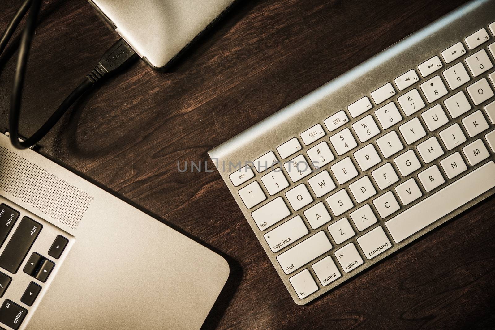 Entrepreneur Work Desk. Modern Working Desk. Laptop Computer, Wireless Keyboard and Portable External Drive. Dark Wooden Desk Top View