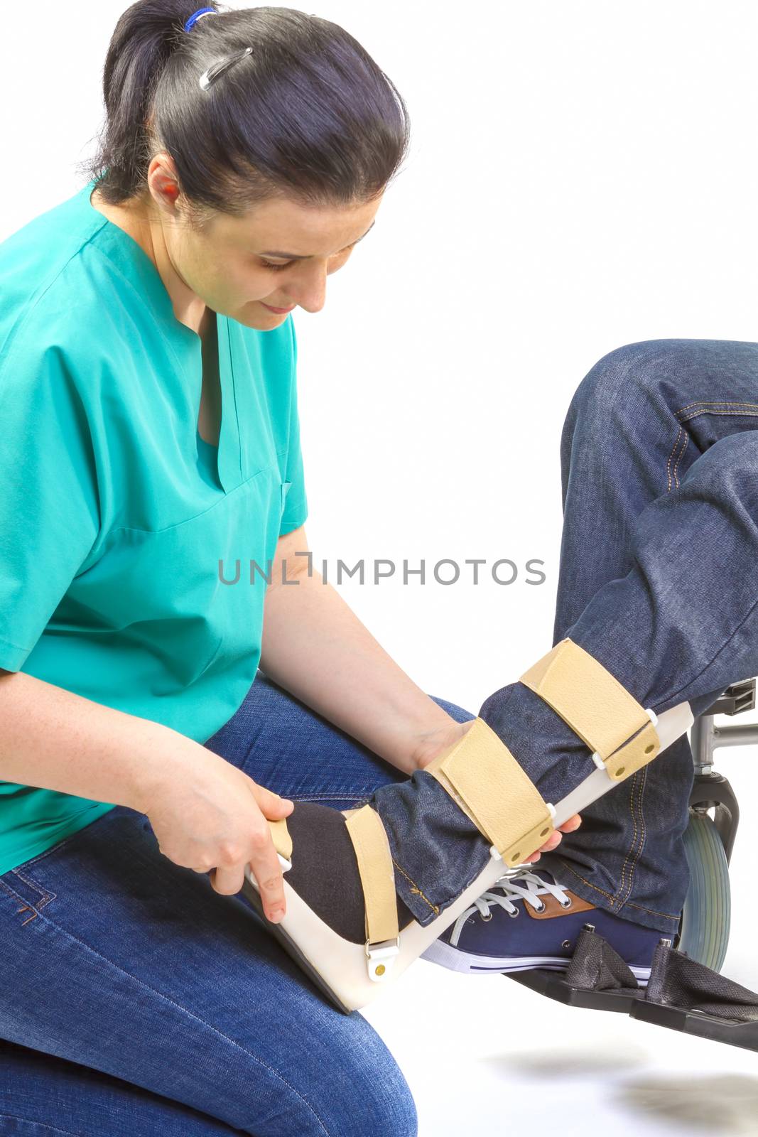 Orthopedist puts orthosis to patient in wheelchair with disabilities